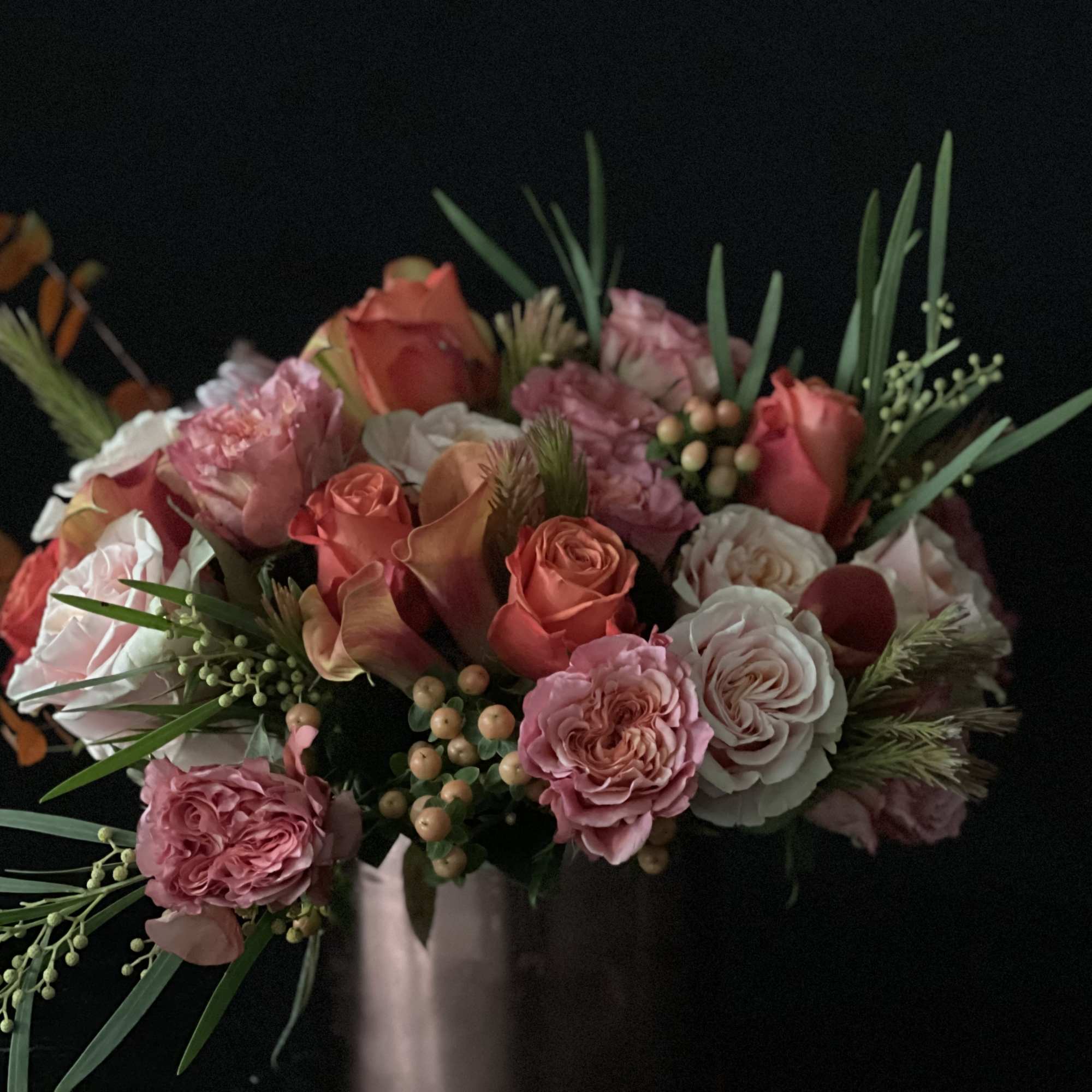 Pink and coral rose bouquet with calla lilies in a vase