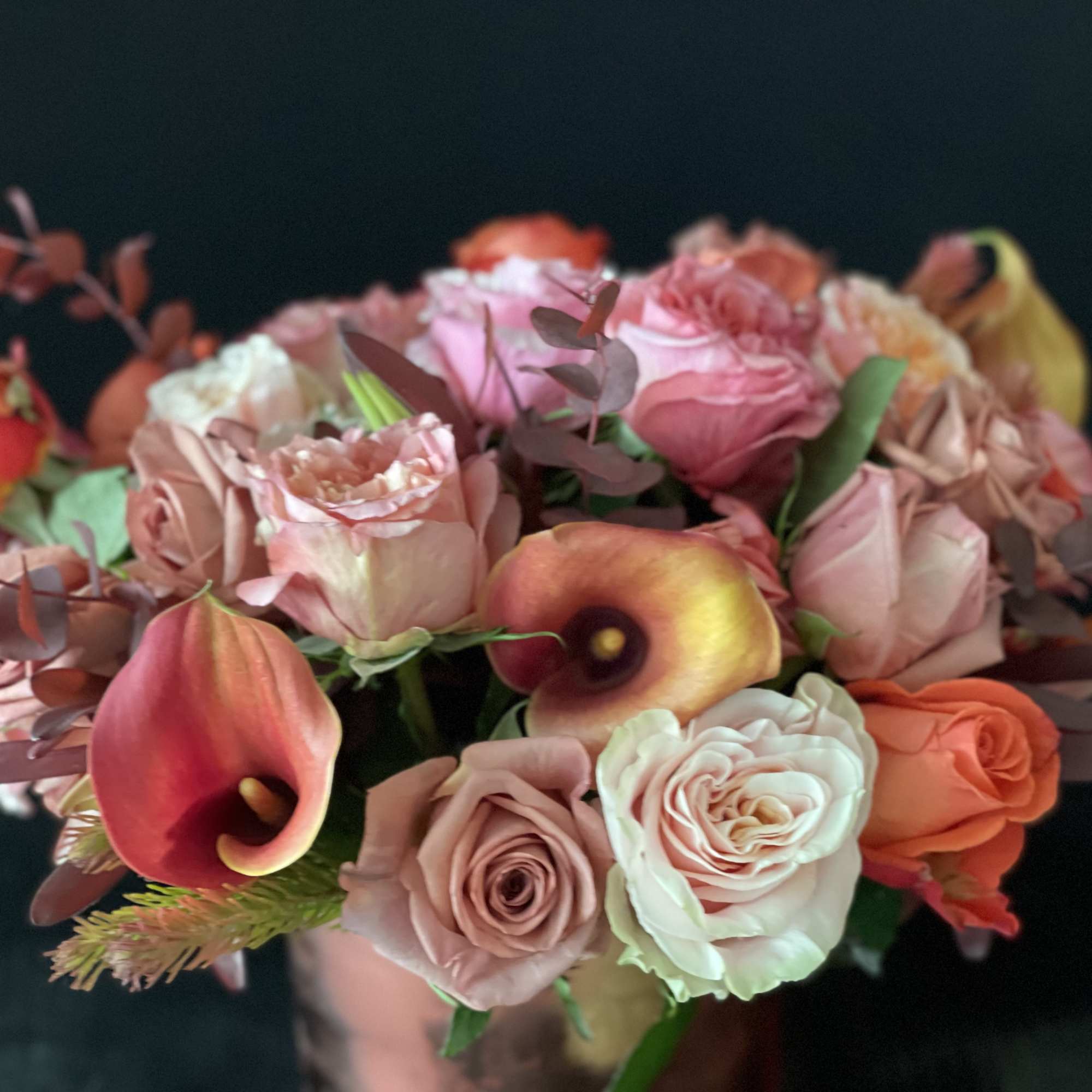 Pink and peach roses with calla lilies in a vase