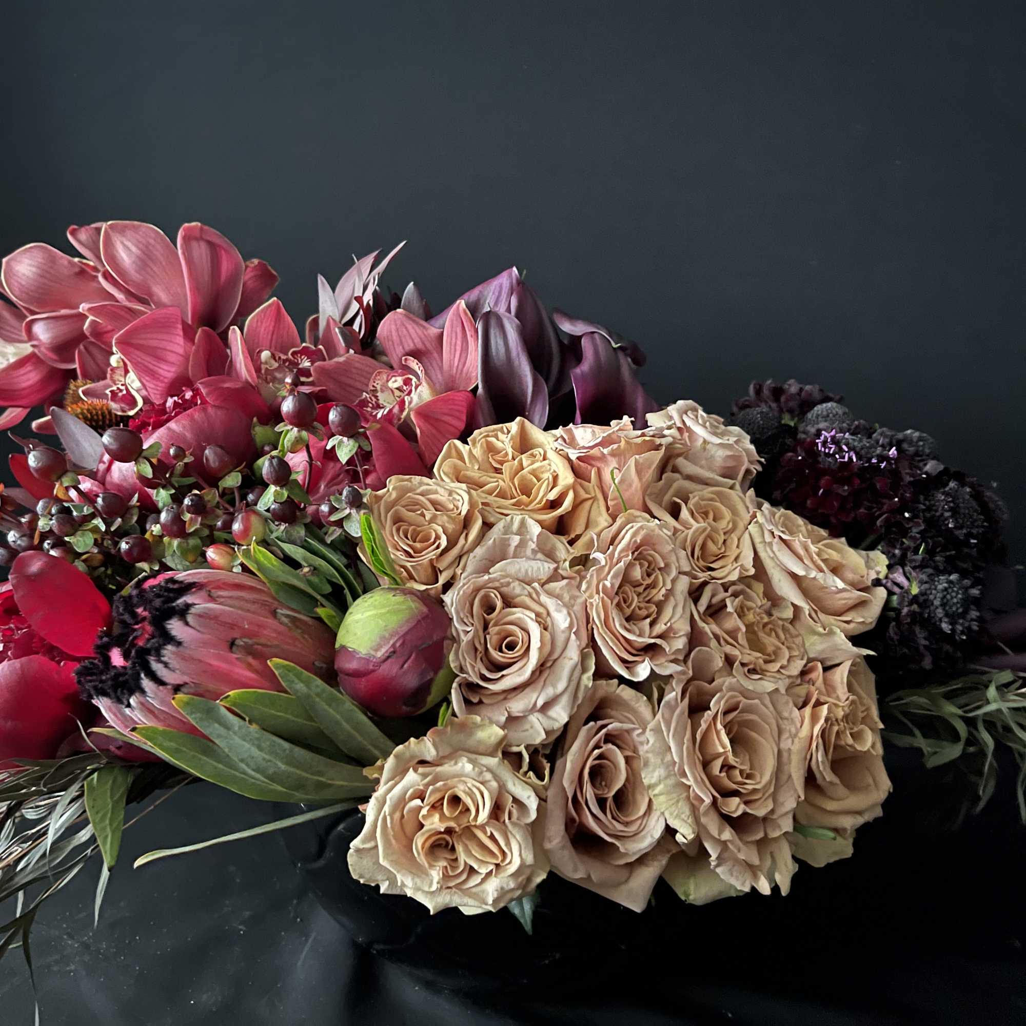 Bouquet of blush roses and pink orchids with dark accents