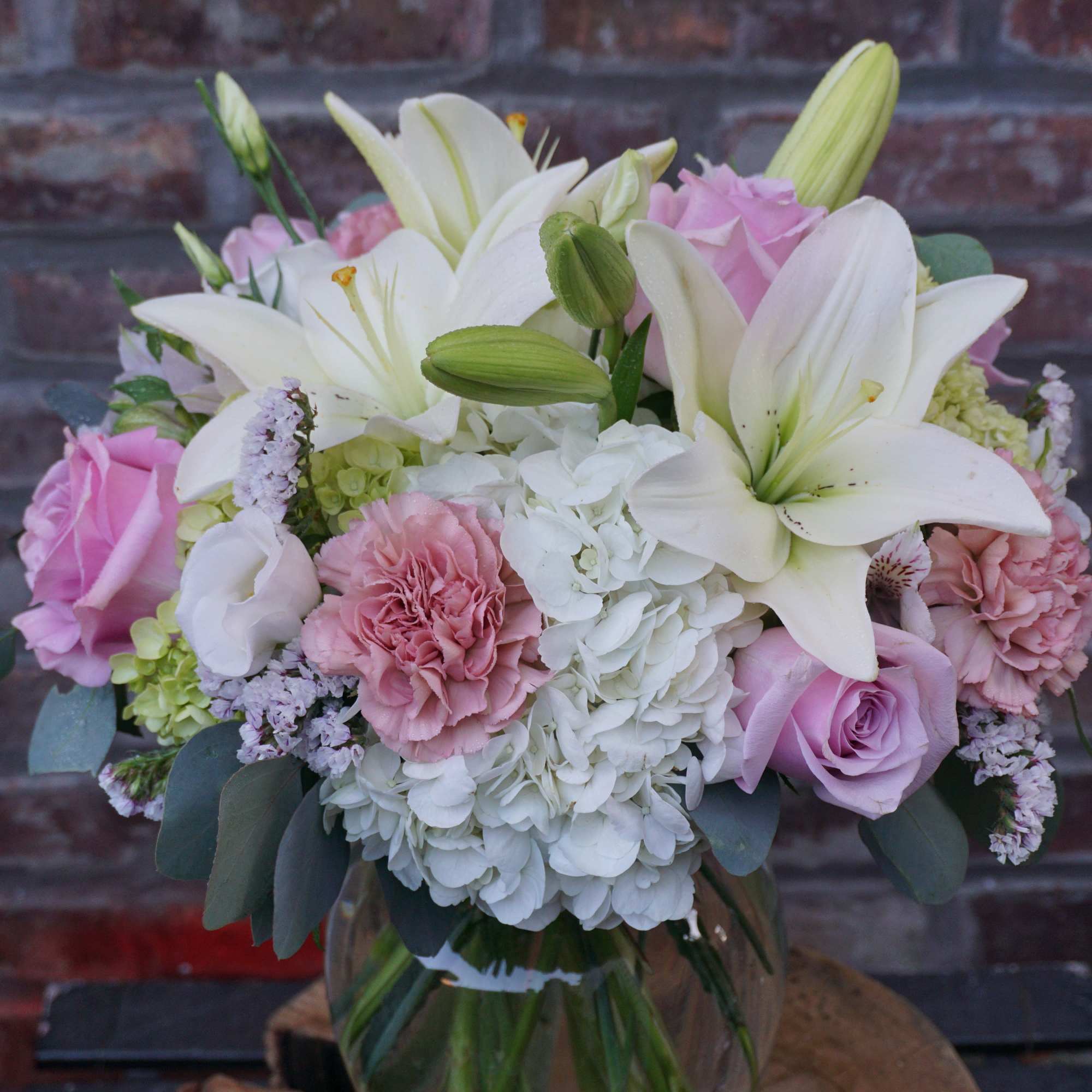 Bouquet of white lilies, pink roses, and hydrangeas in a glass vase