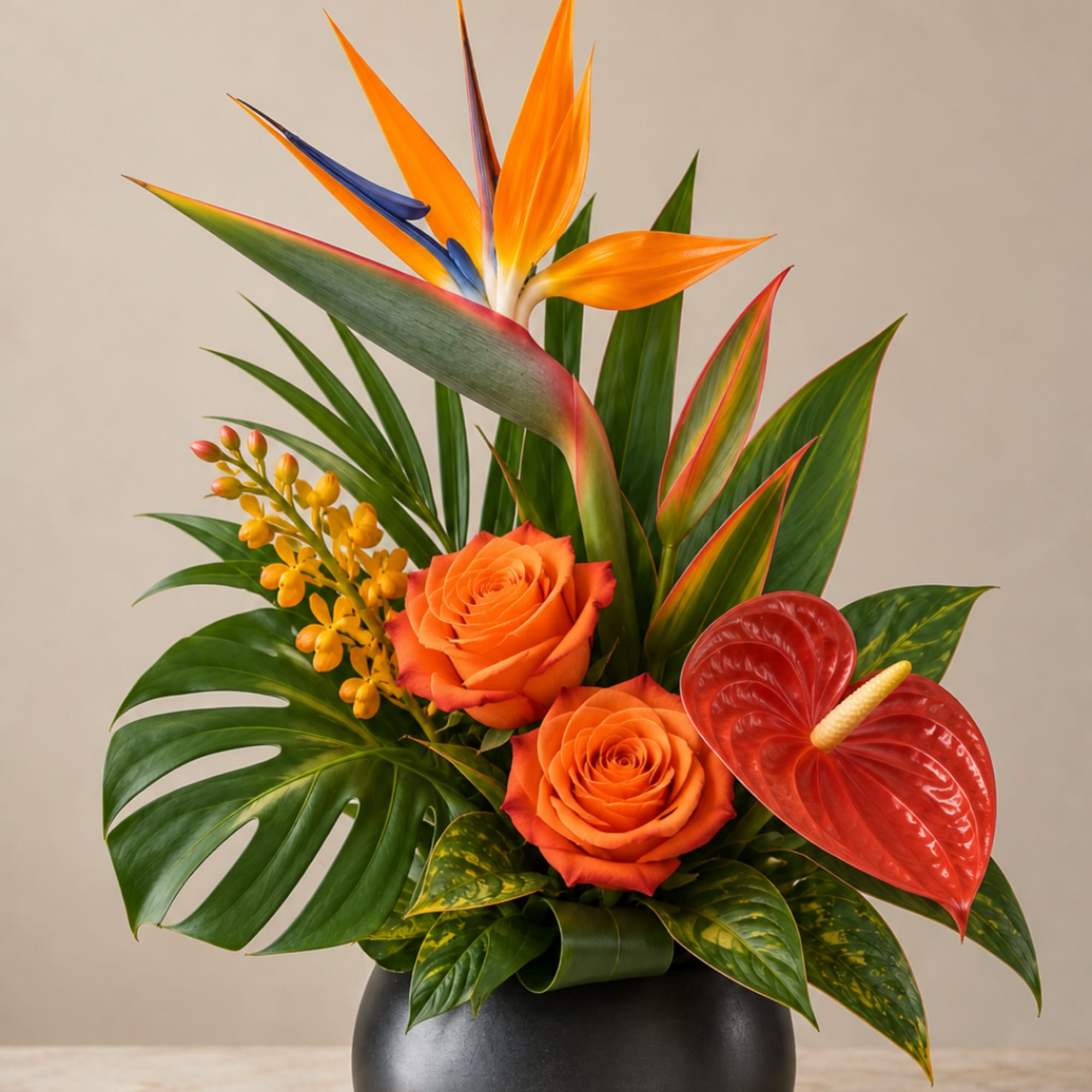 Tropical arrangement with orange roses, bird of paradise, and red anthurium in a black vase