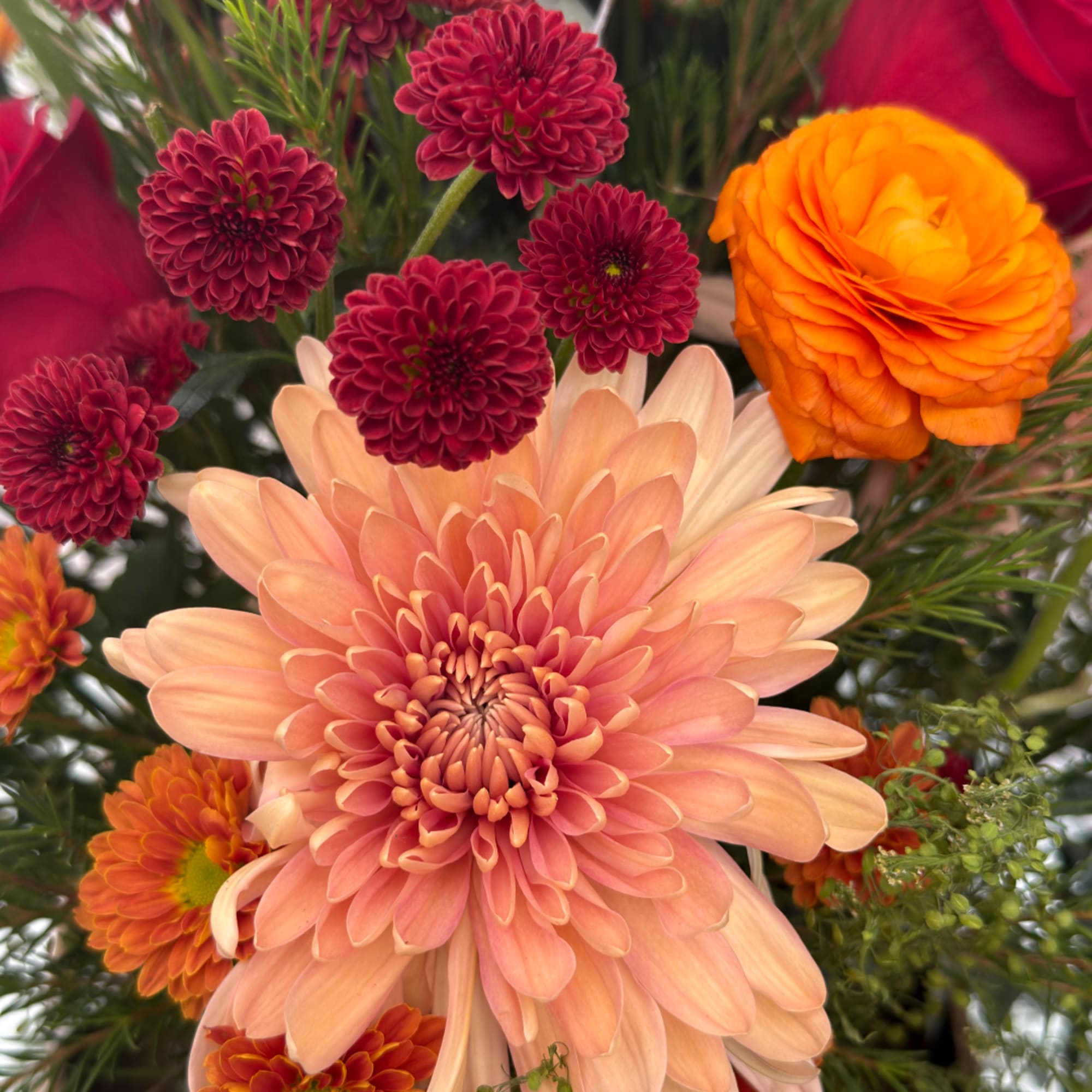 Peach and orange flowers with burgundy pompon blooms in a bouquet