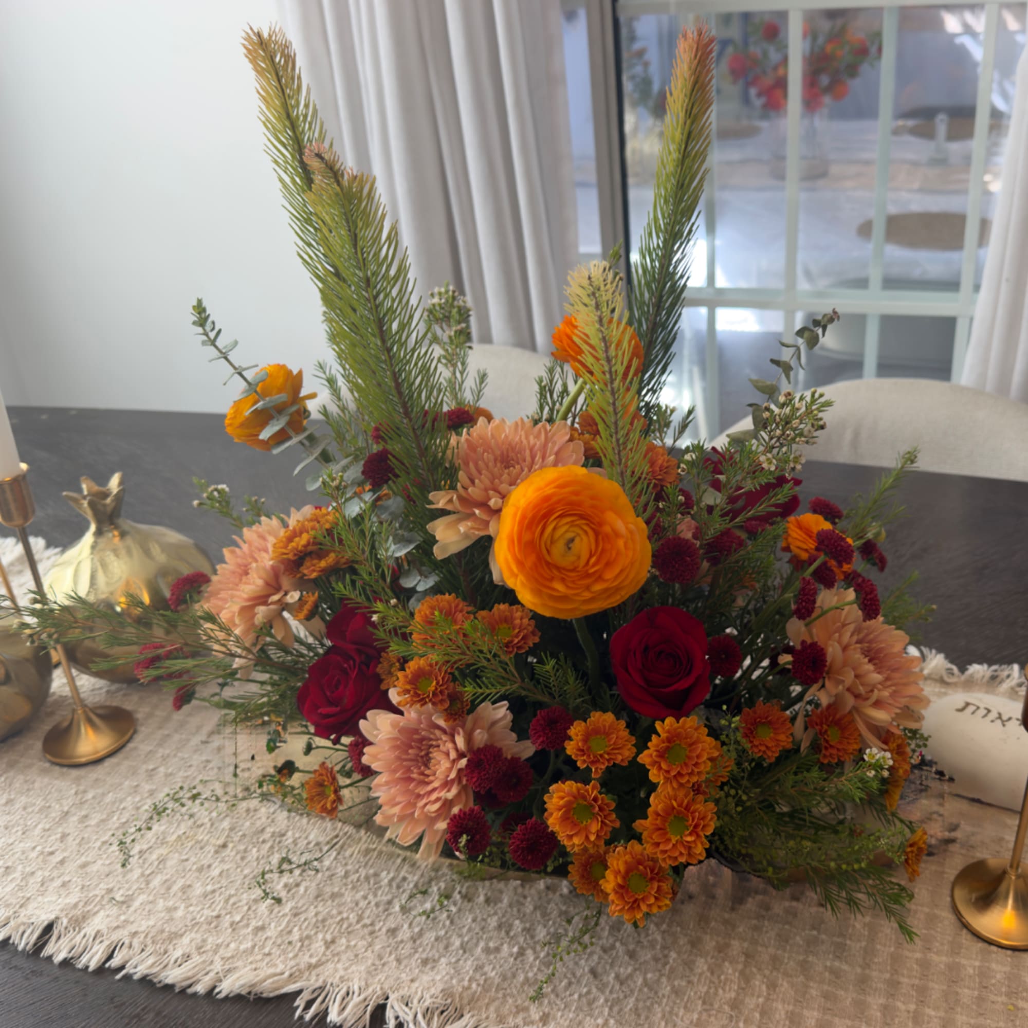 Mixed orange, red, and peach floral centerpiece in a low arrangement