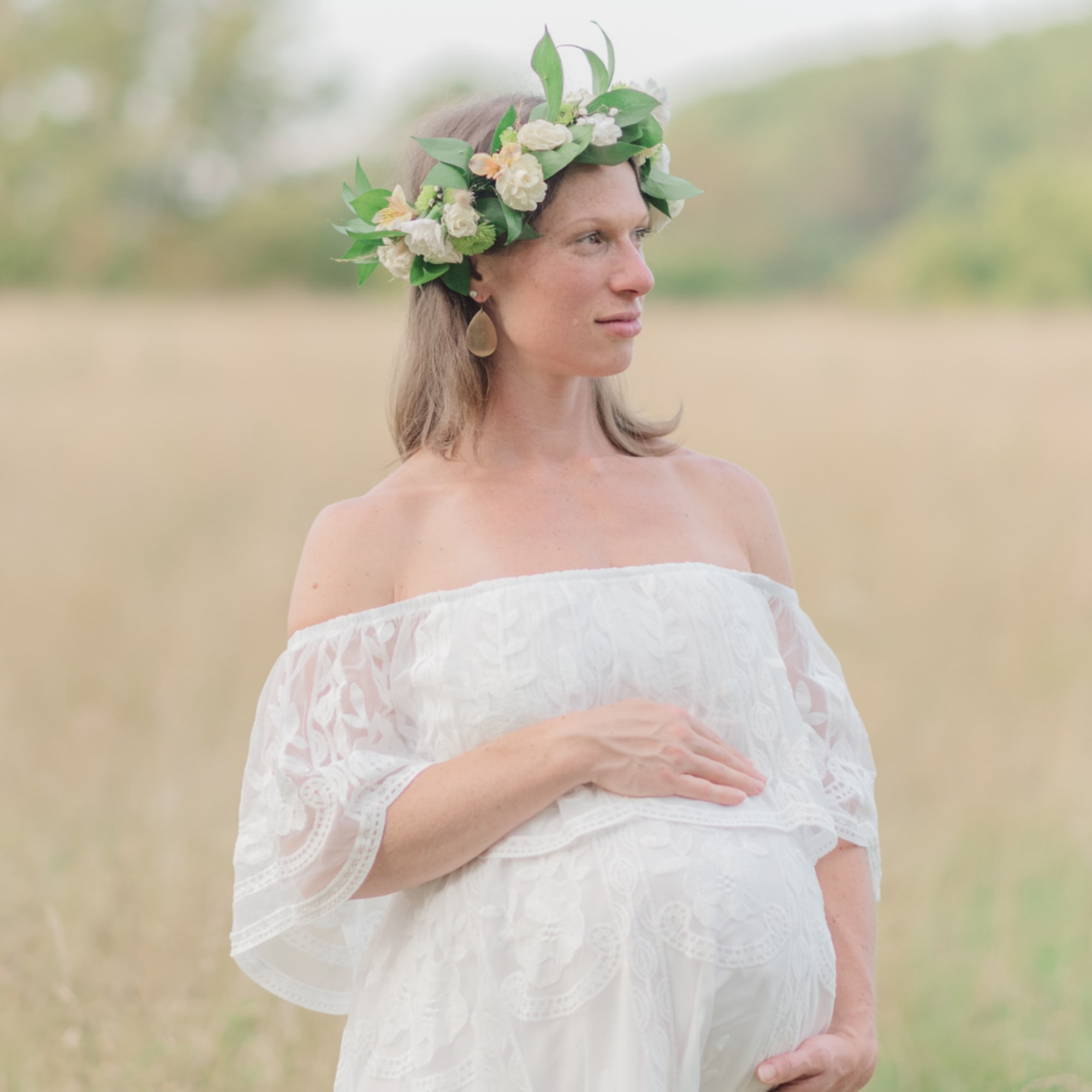 Pregnant woman wearing a white dress and floral crown outdoors