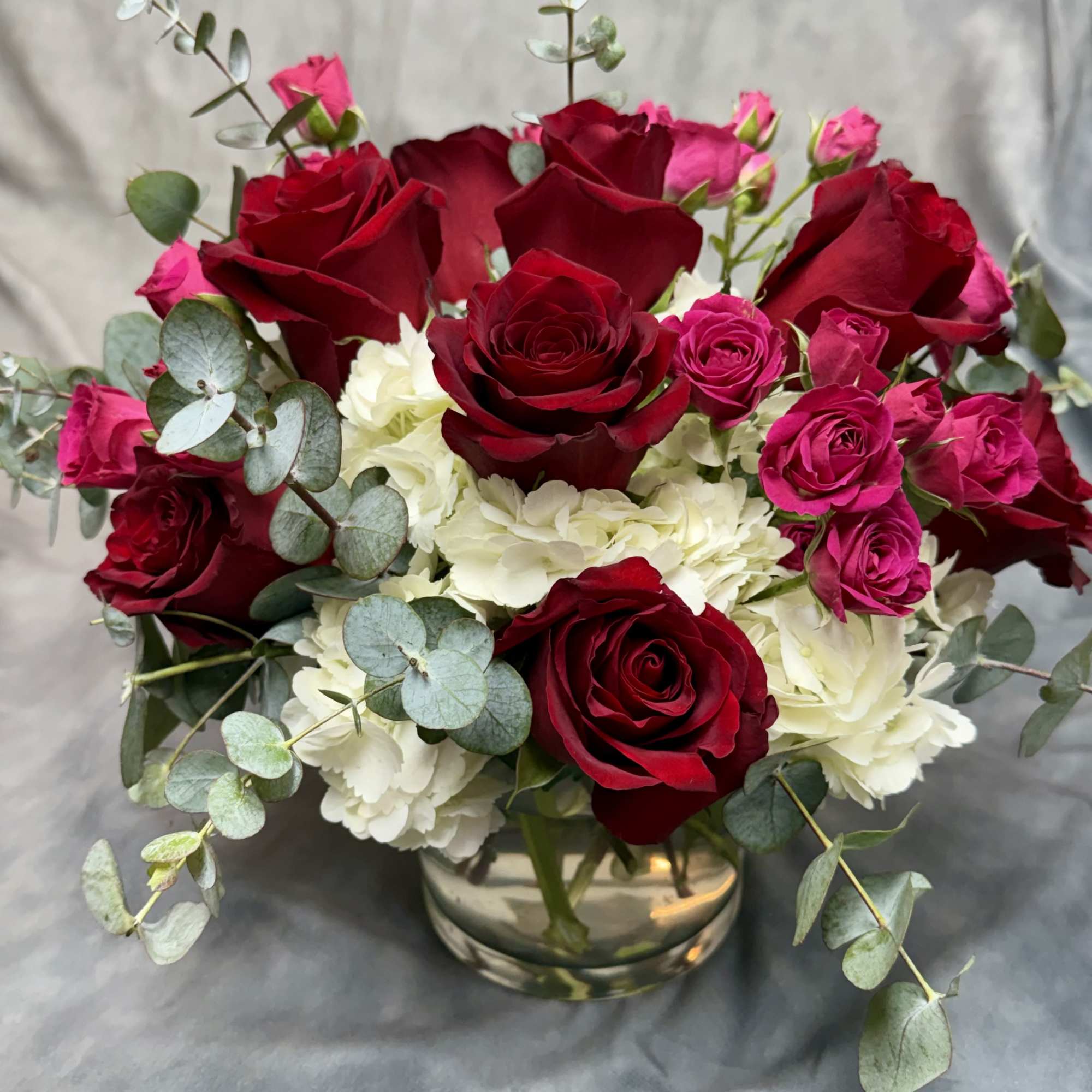 Red and pink roses with white hydrangeas in a glass vase