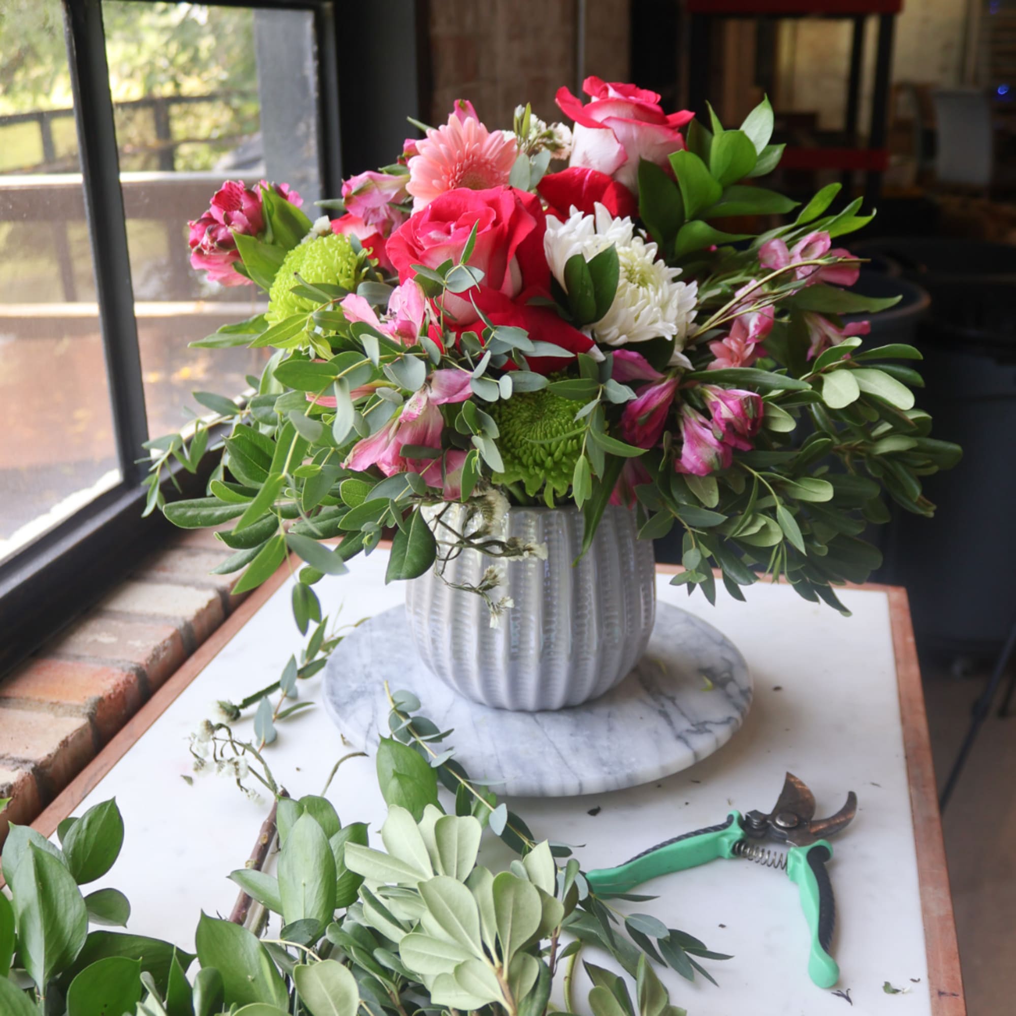 Mixed pink and white flower arrangement in a ribbed vase on a marble base