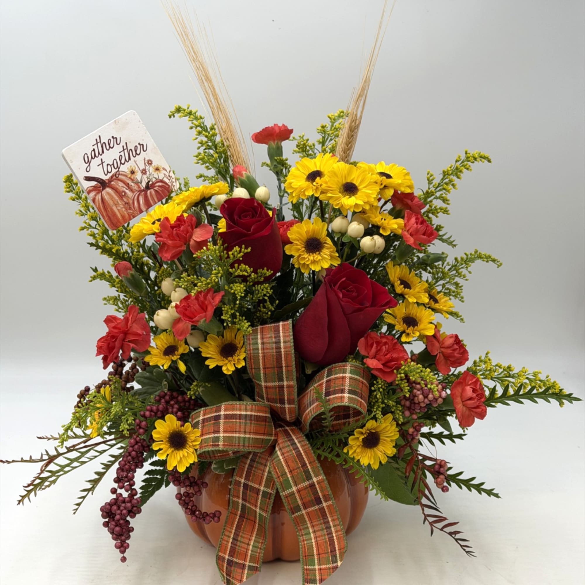 Fall floral arrangement in a pumpkin container with roses and daisies