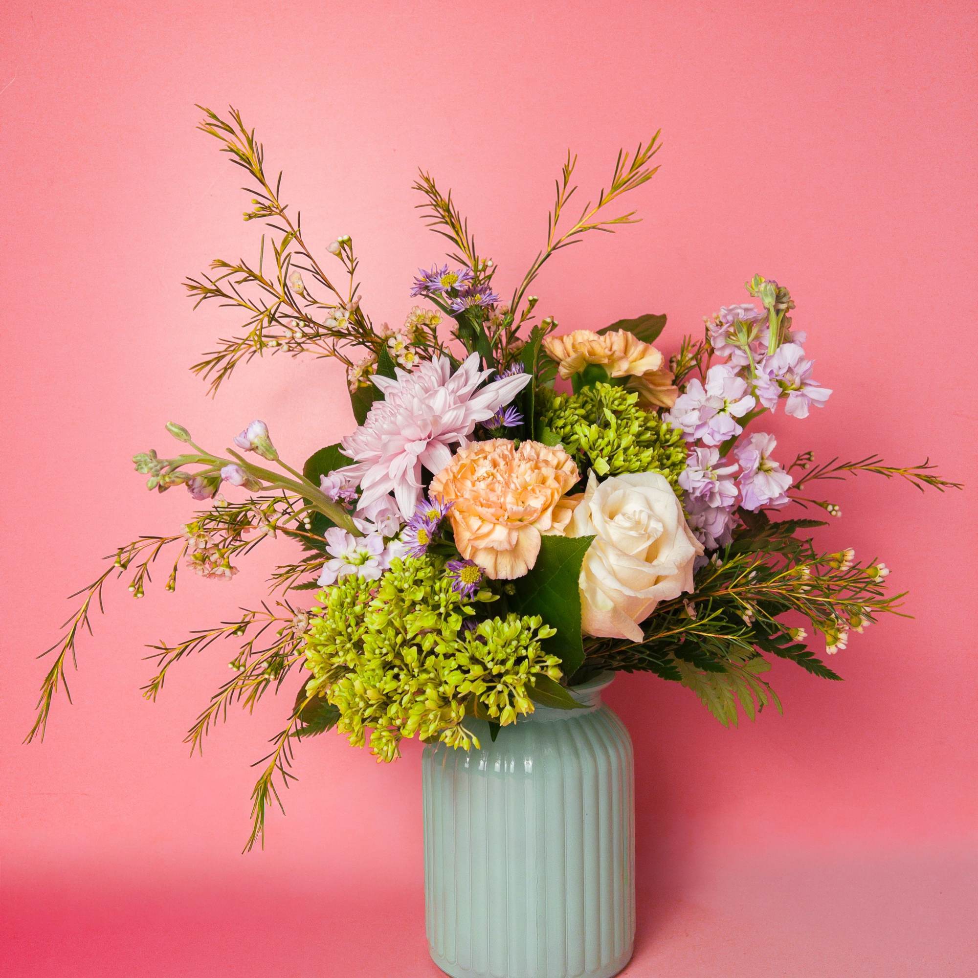 A soft, garden-fresh bouquet in peaches, creams, lavenders and bright spring green.