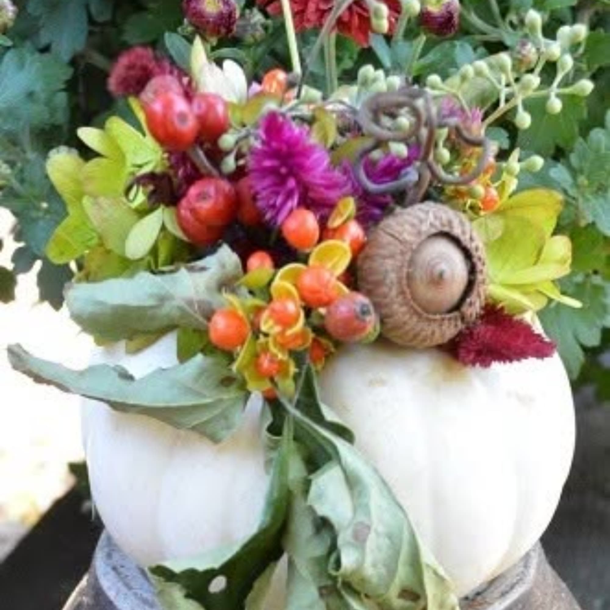 Mixed floral arrangement in a white pumpkin-shaped container with an acorn accent