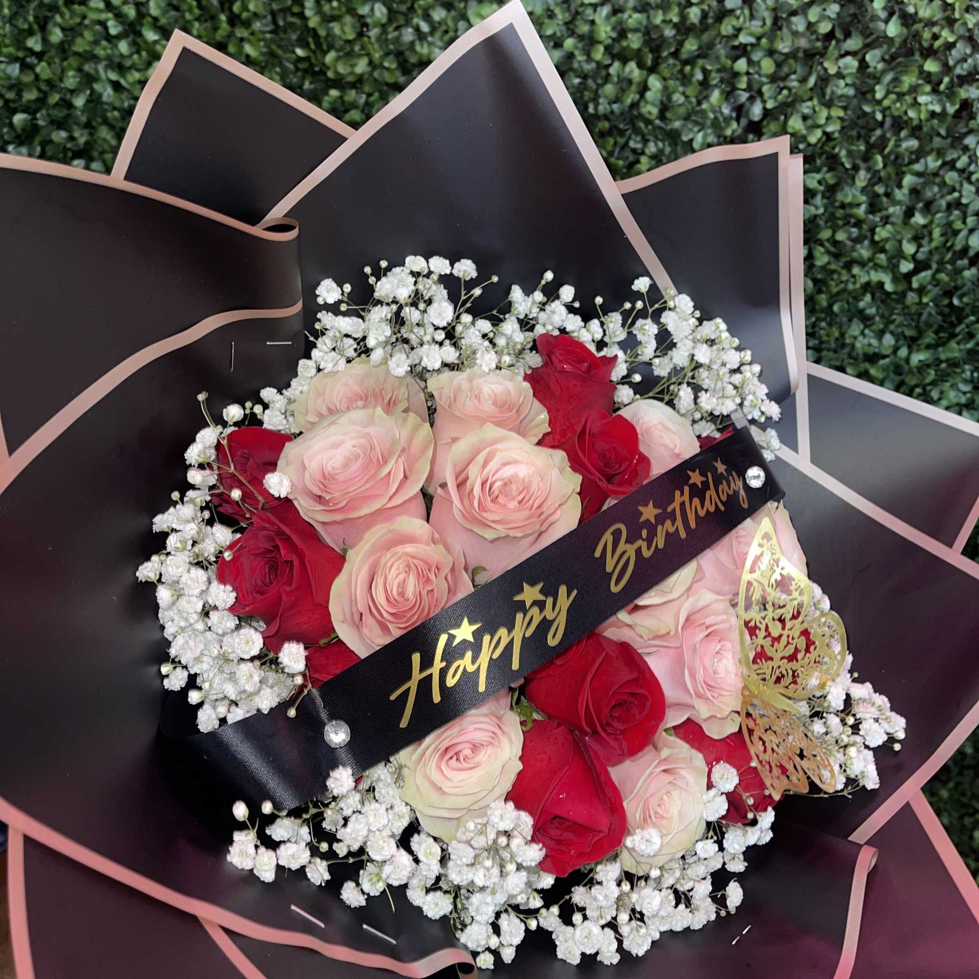 Bouquet of pink and red roses with baby's breath and a birthday ribbon