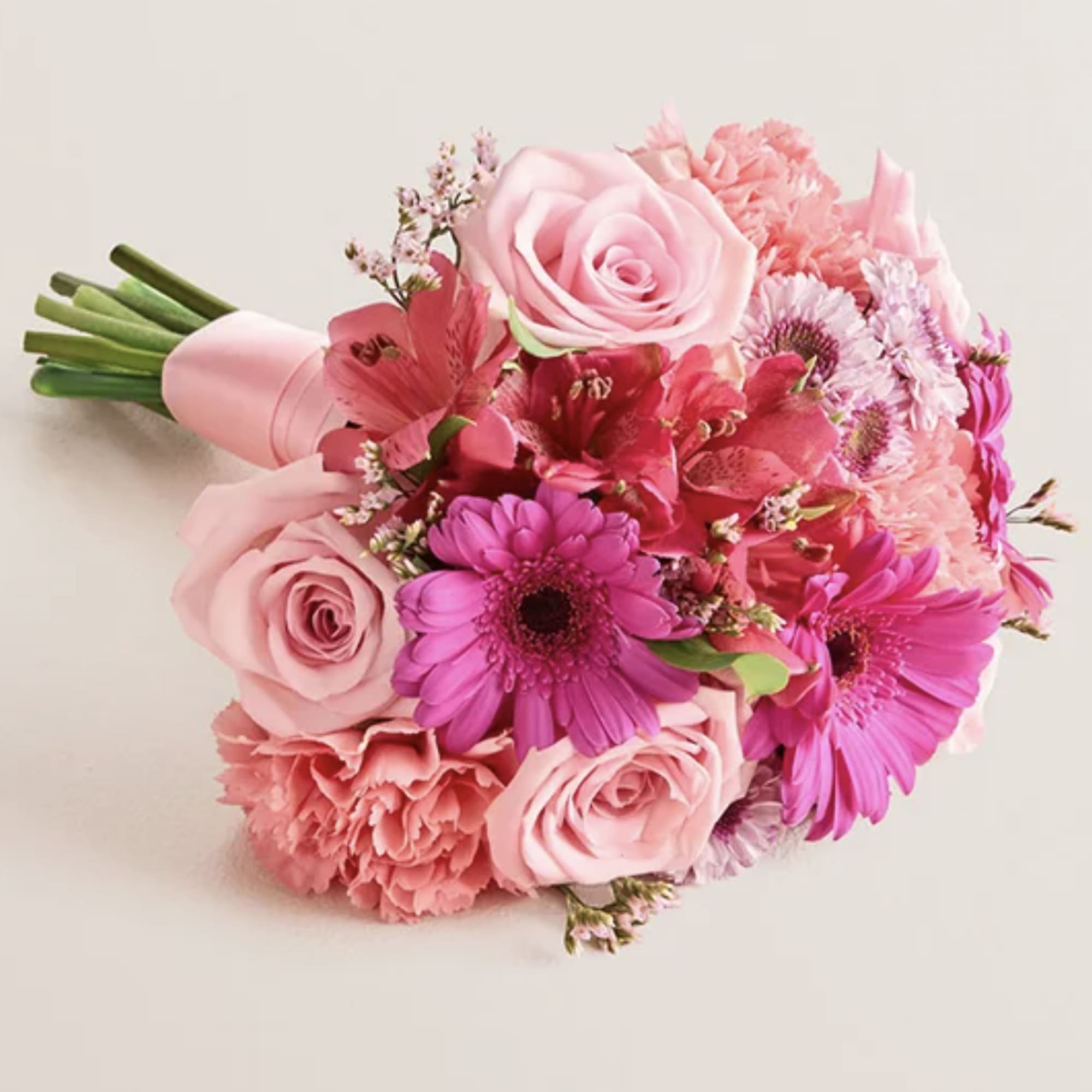 Pink bouquet of roses, gerbera daisies, and carnations wrapped in pink paper