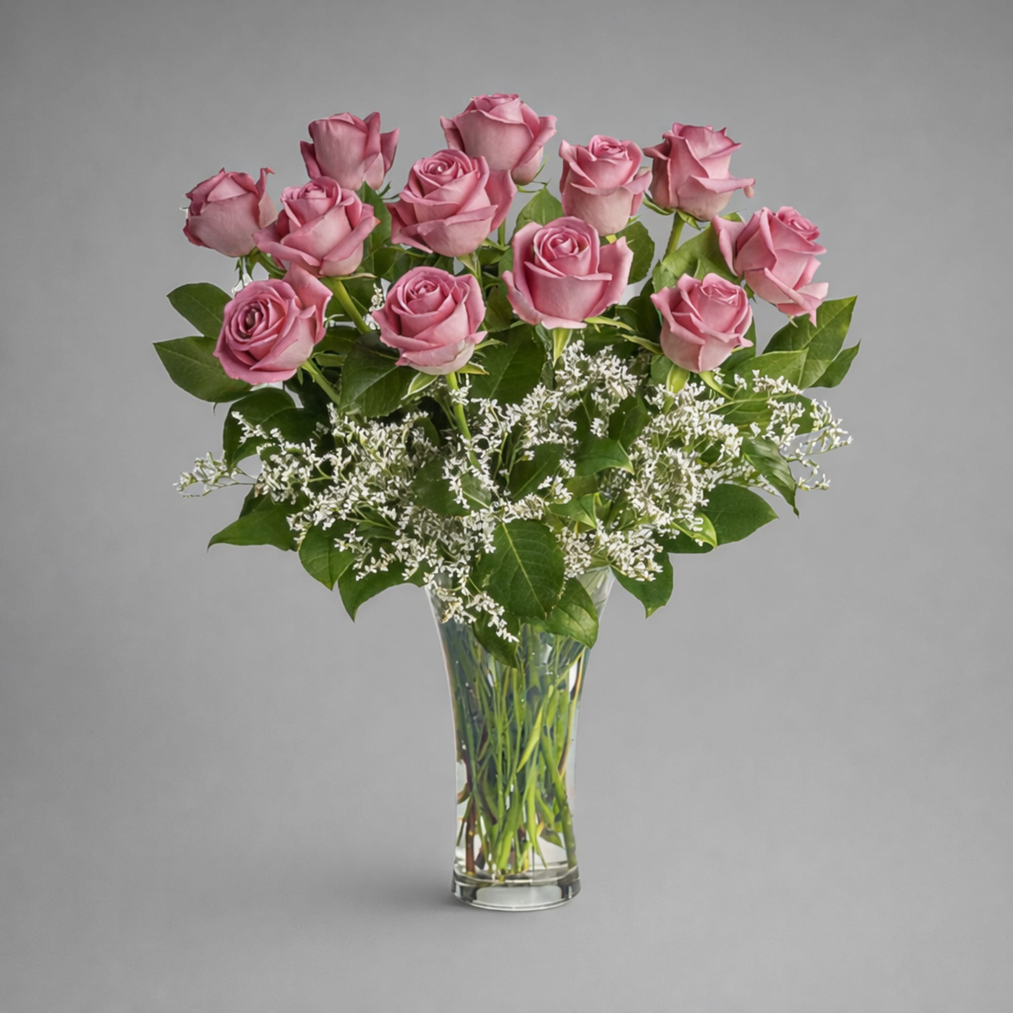 Pink roses arranged in a clear glass vase with white filler flowers