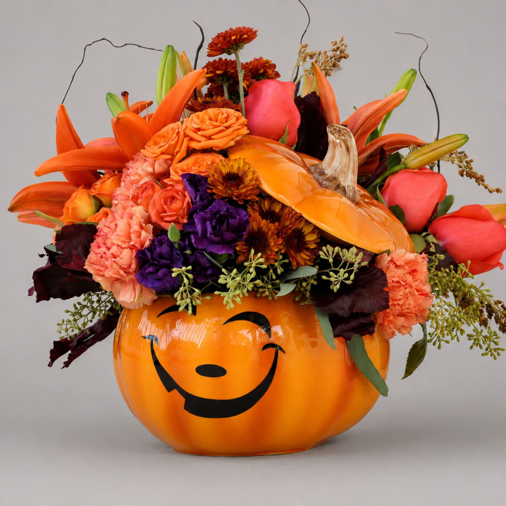 Orange pumpkin container filled with orange, pink, and purple flowers