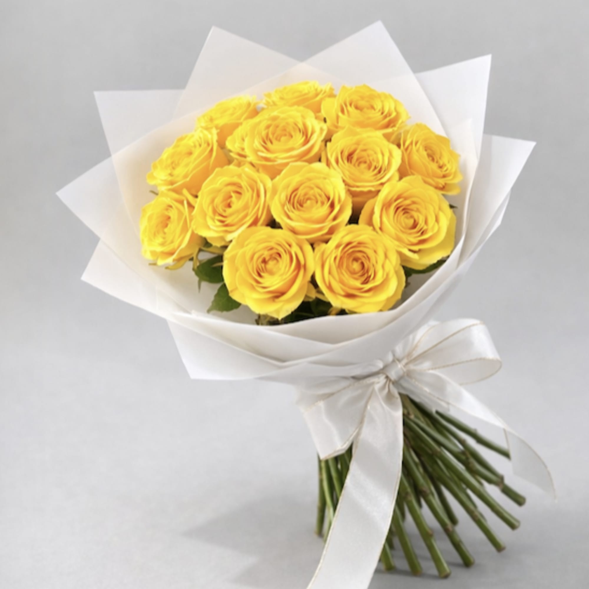 Bouquet of yellow roses wrapped in white paper with a ribbon