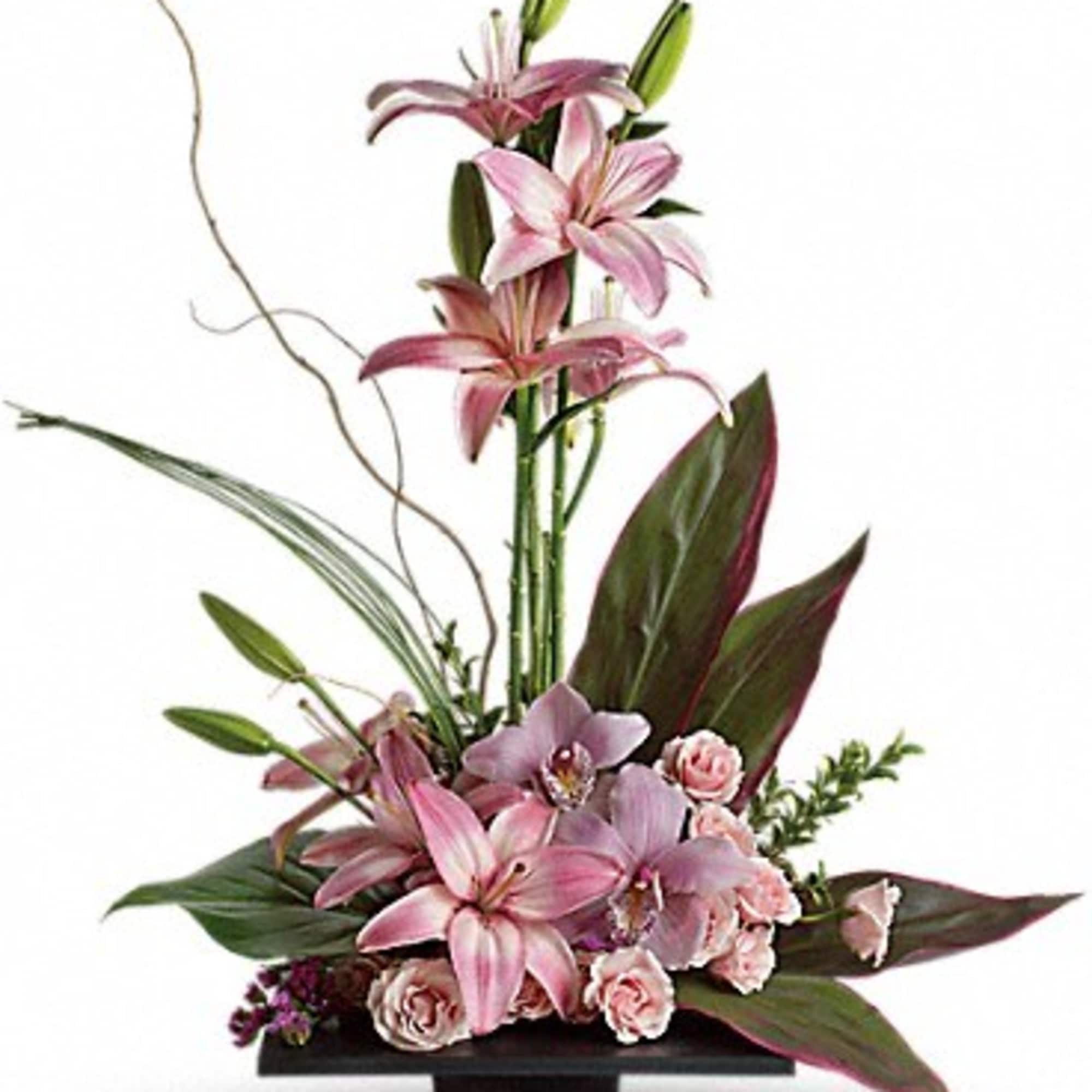 Pink lilies and roses arranged in a black vase with tall leaves
