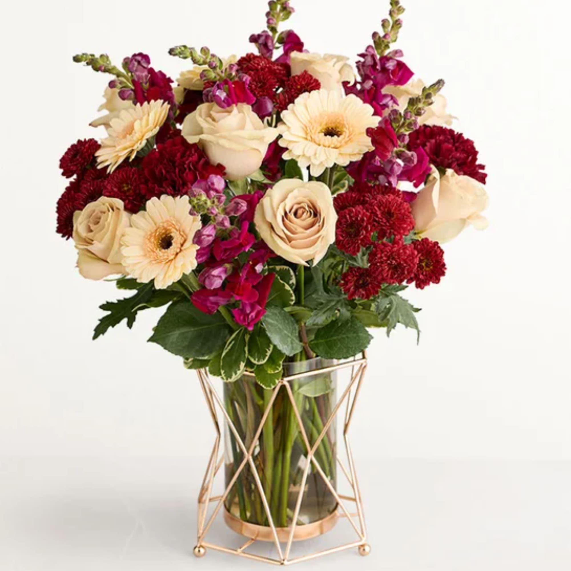 Bouquet of cream roses, white gerbera daisies, and red flowers in a glass vase
