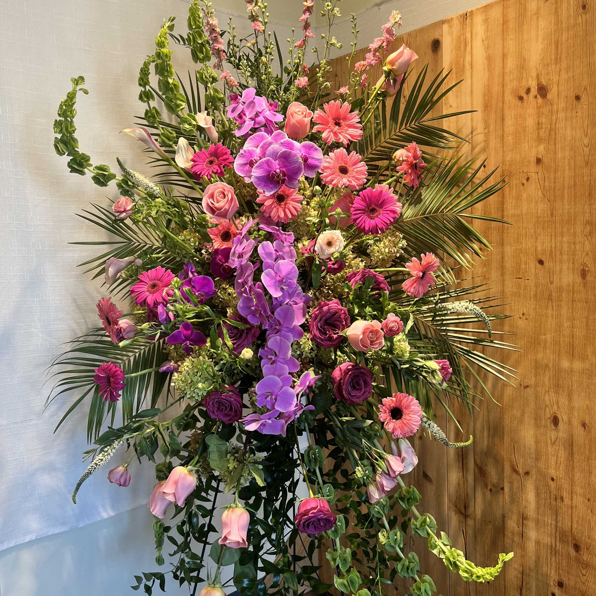 Tall floral arrangement with pink and purple blooms in a stand