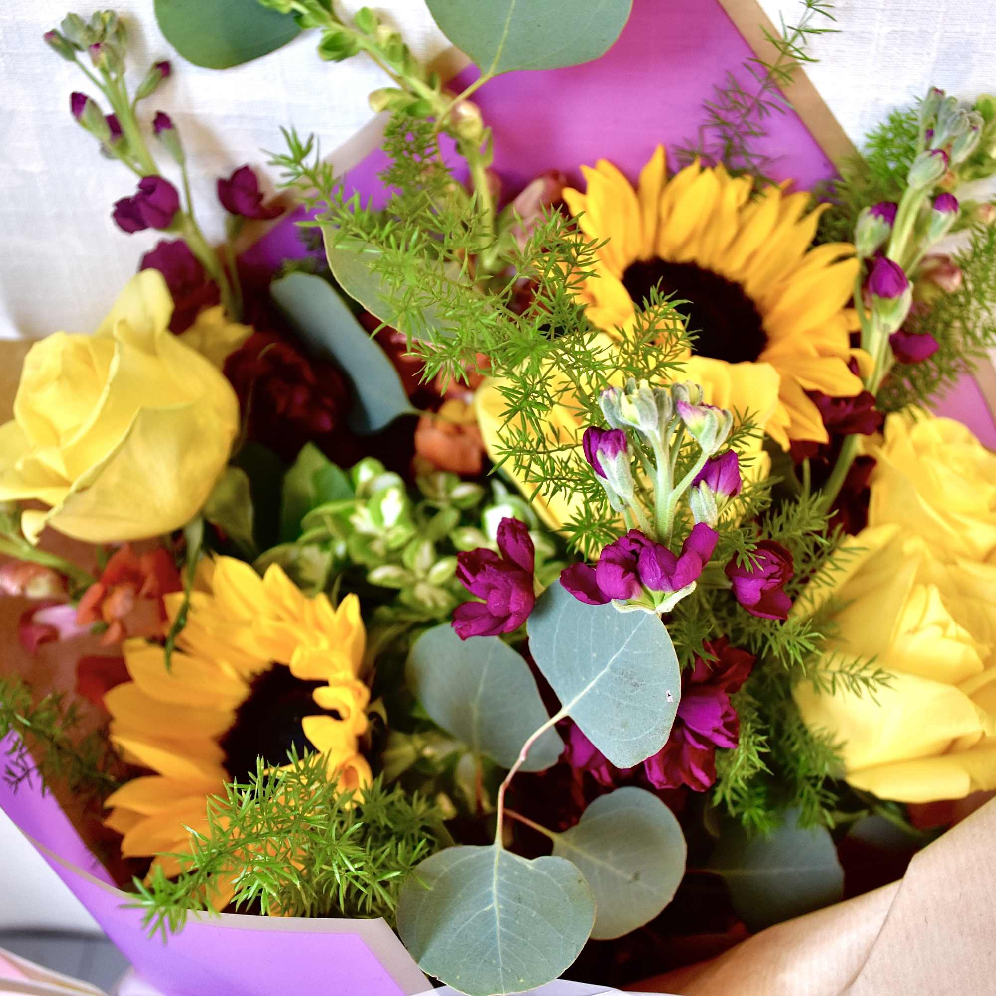 Bouquet of yellow roses and sunflowers with purple accents