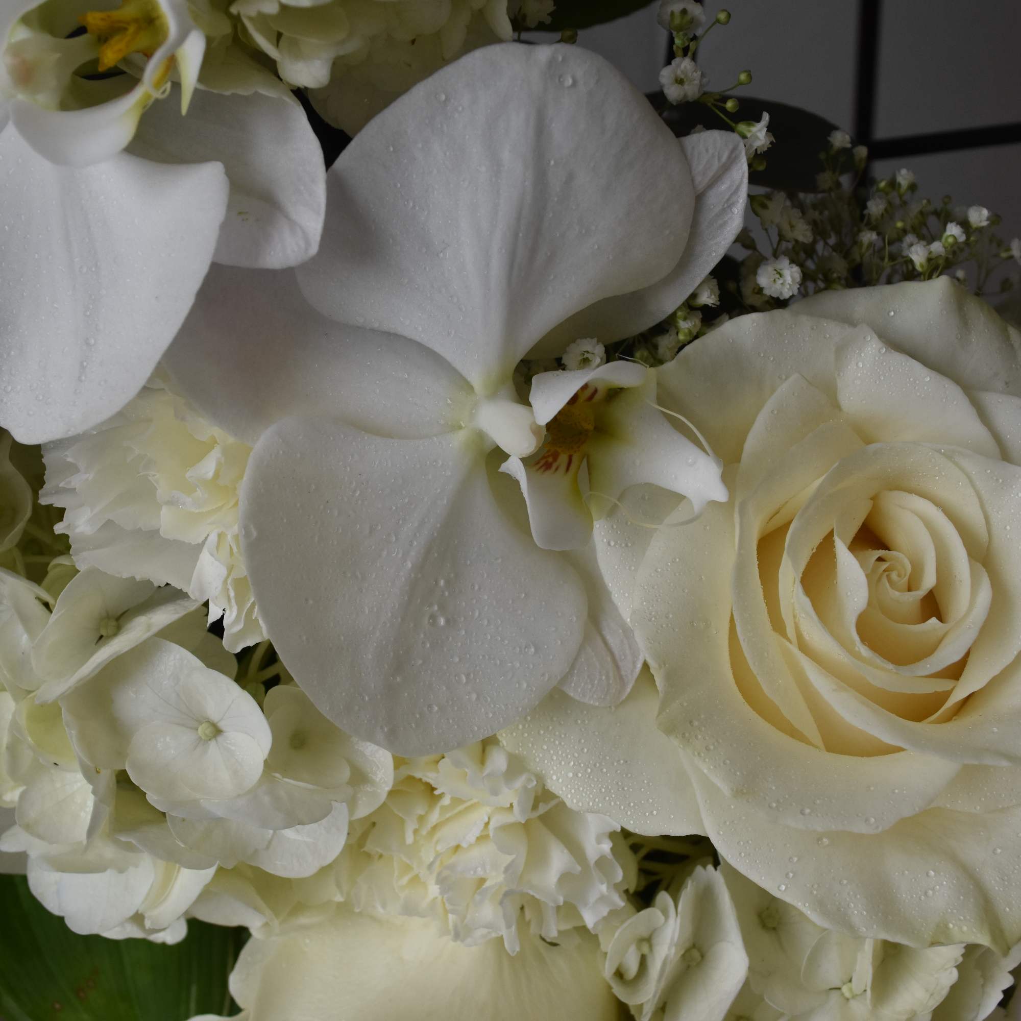 White roses and orchids in a green vase