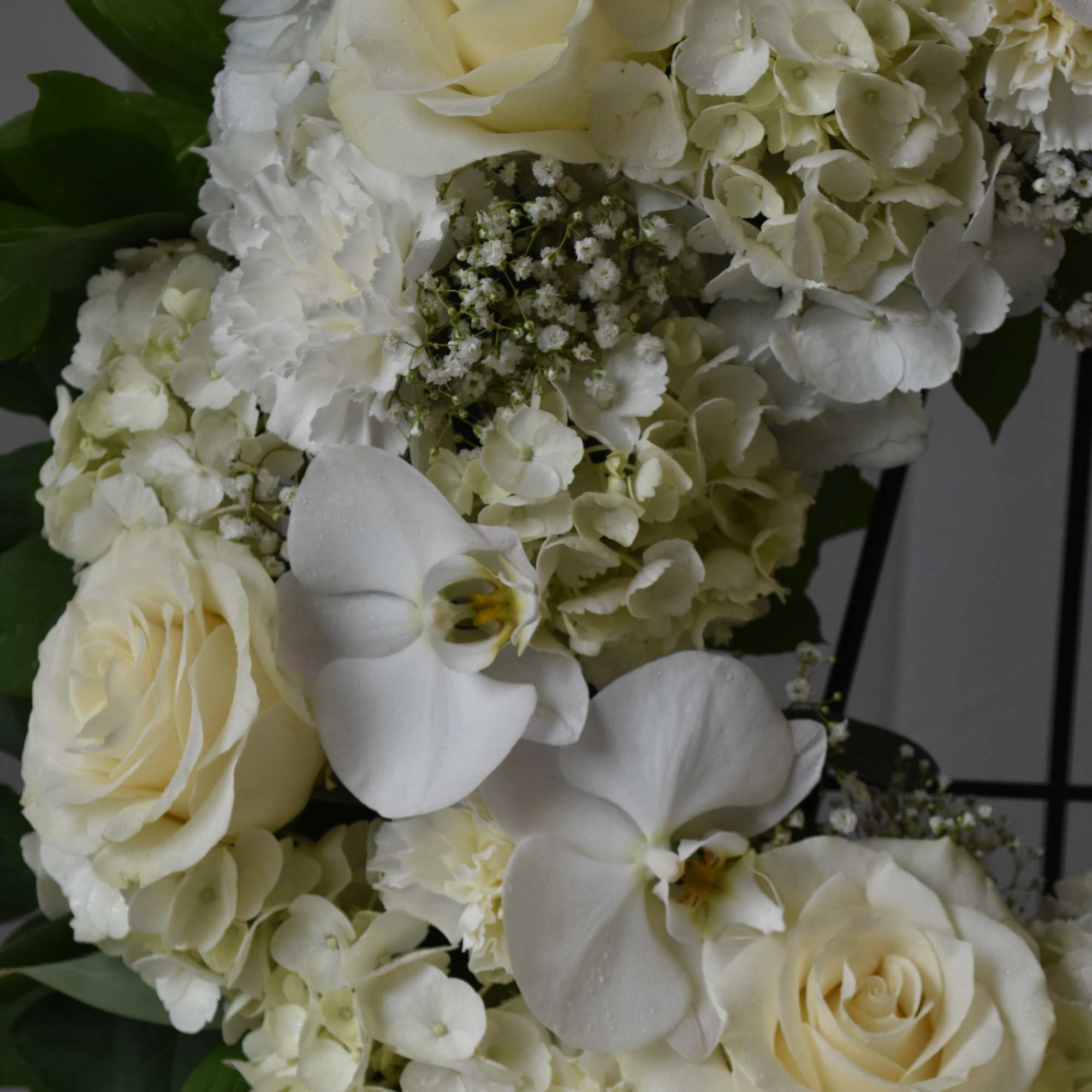 White roses and orchids arranged with pale hydrangeas