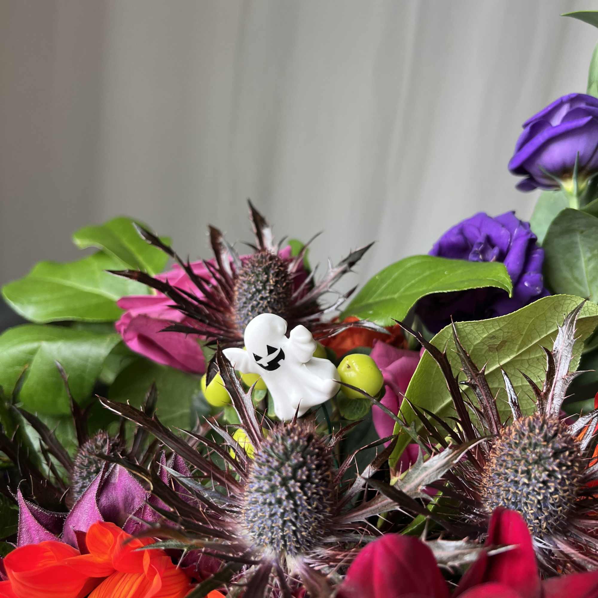 Colorful bouquet with purple, pink, and red flowers and a small ghost charm