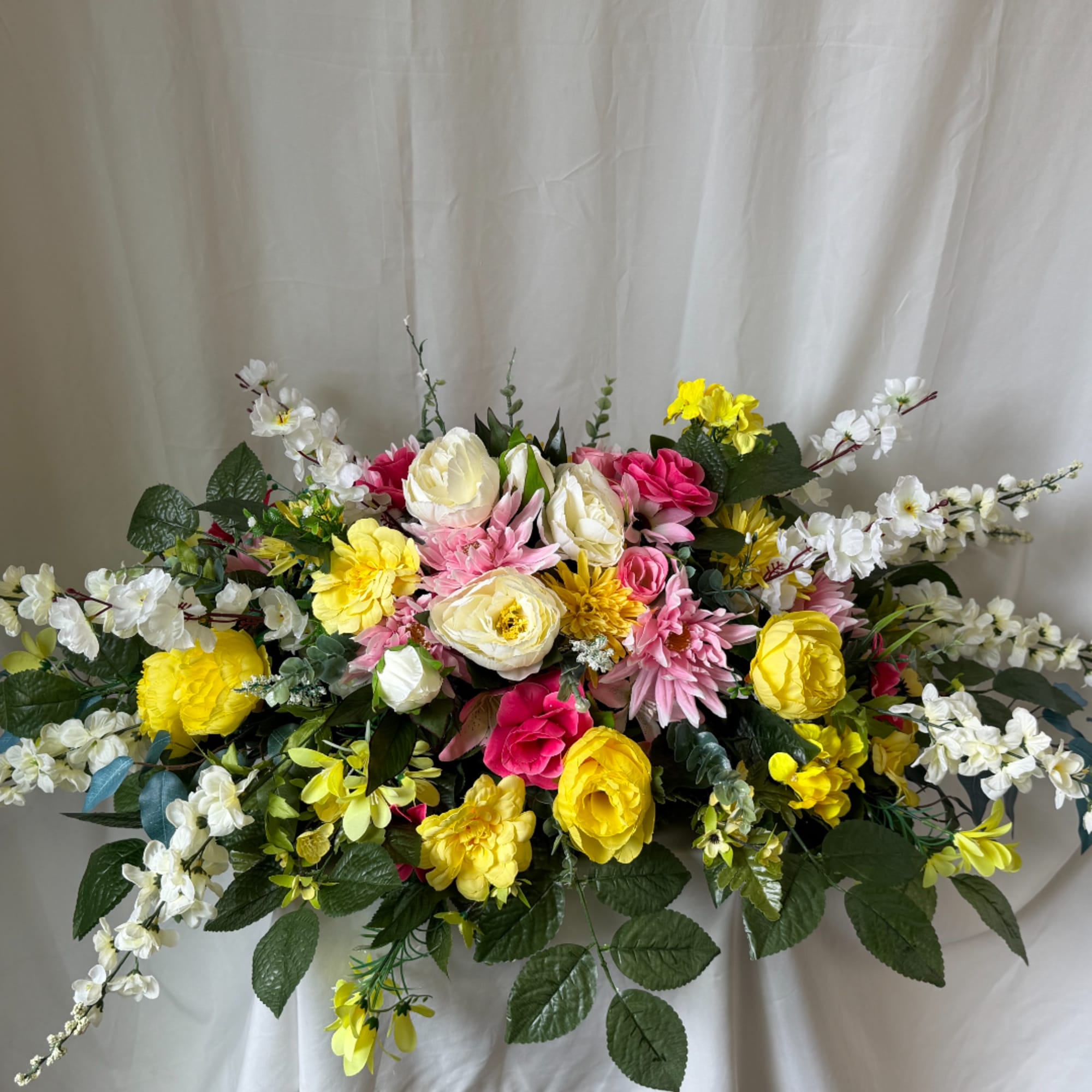 Large mixed bouquet with yellow, pink, and white flowers against a light backdrop