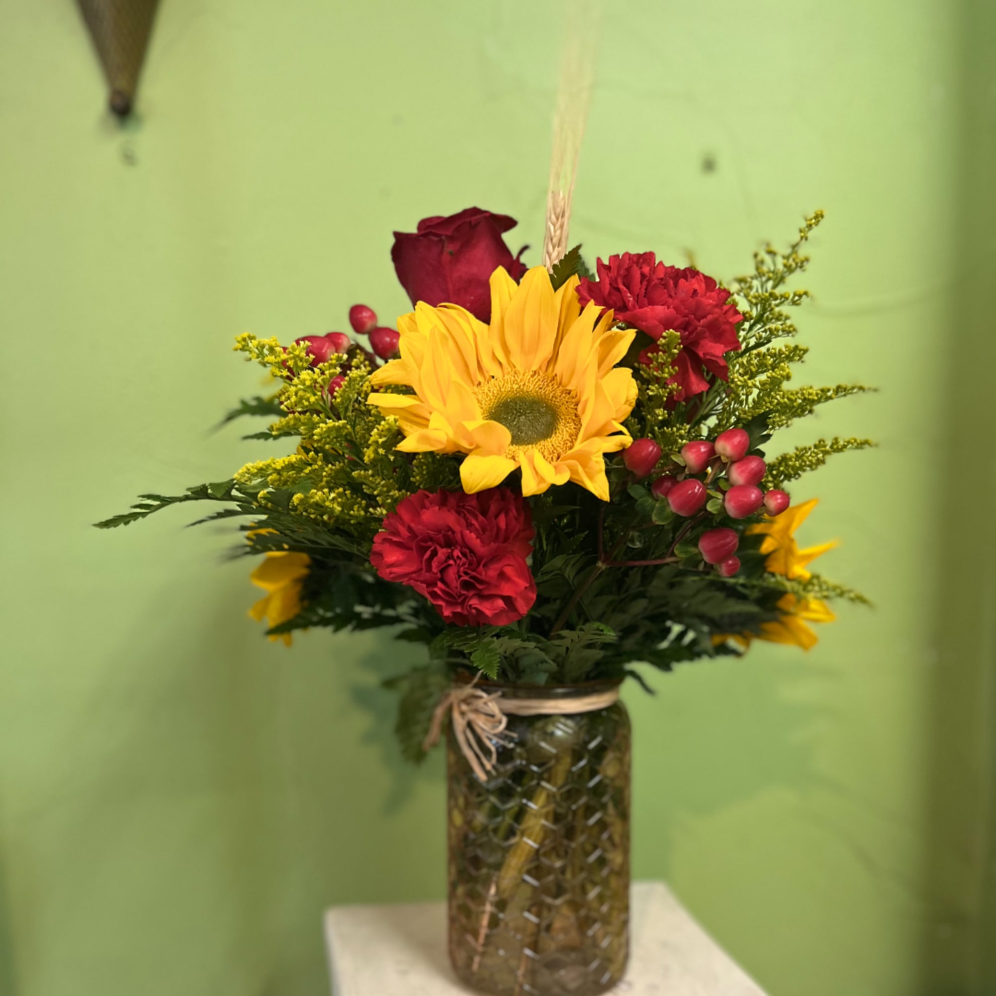 Sunflower and red carnation bouquet in a glass jar vase