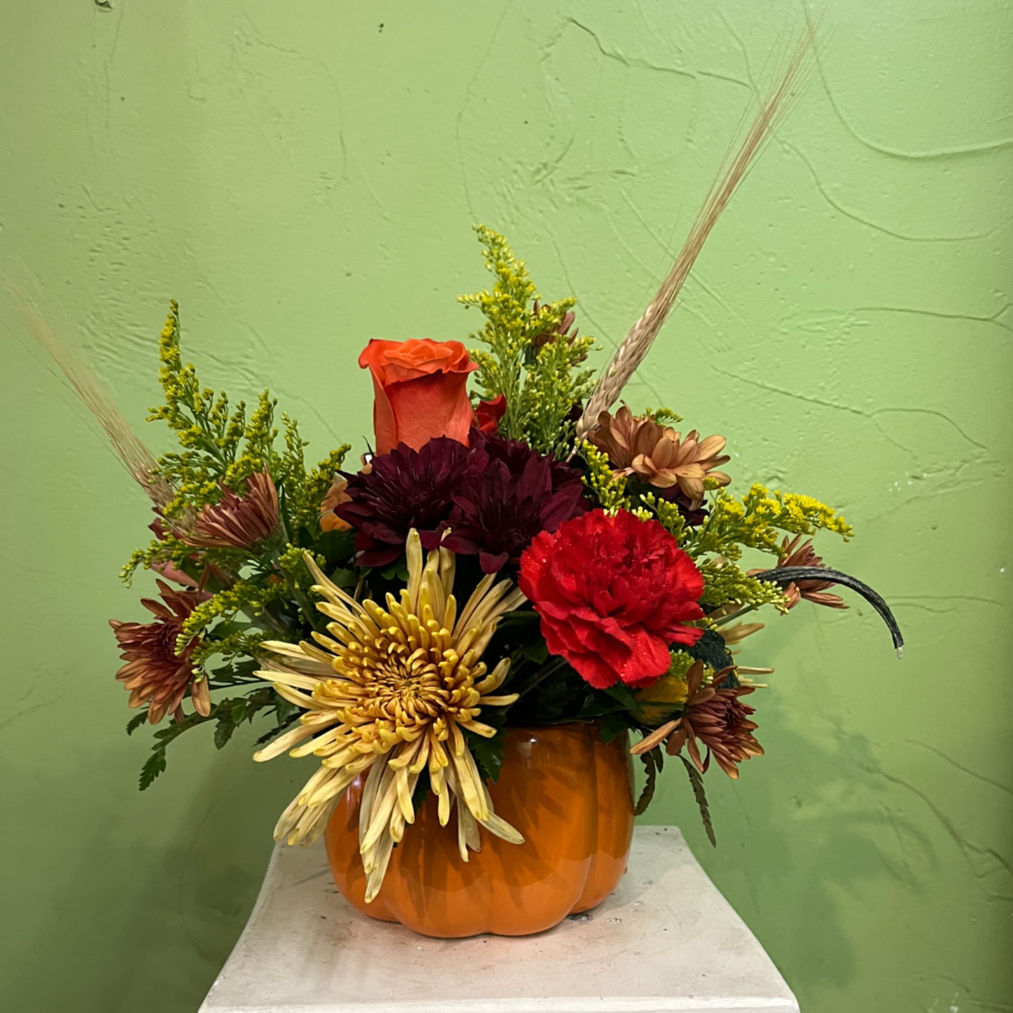 Autumn floral arrangement in an orange pumpkin vase with mixed blooms