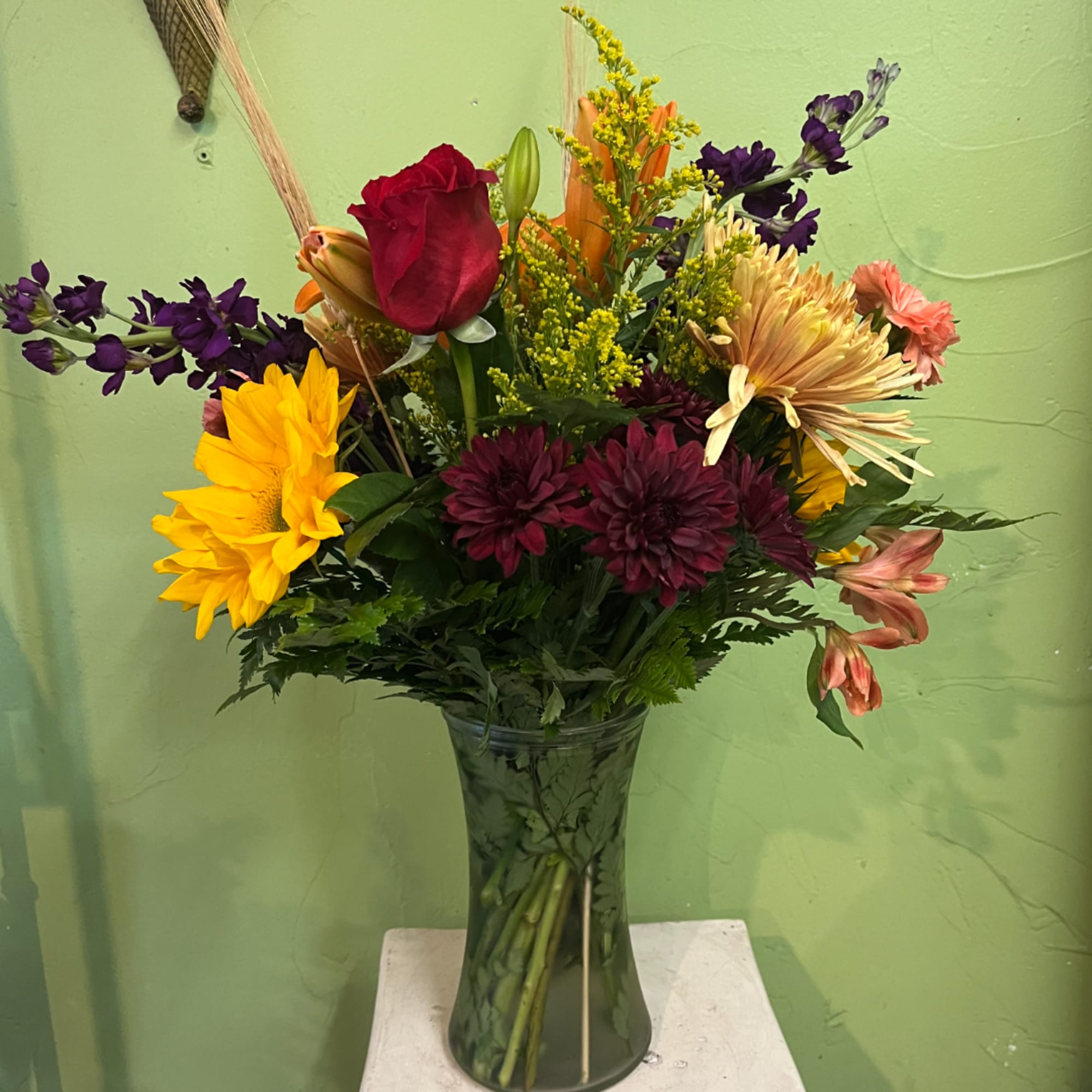 Mixed bouquet of roses, sunflowers, and chrysanthemums in a glass vase