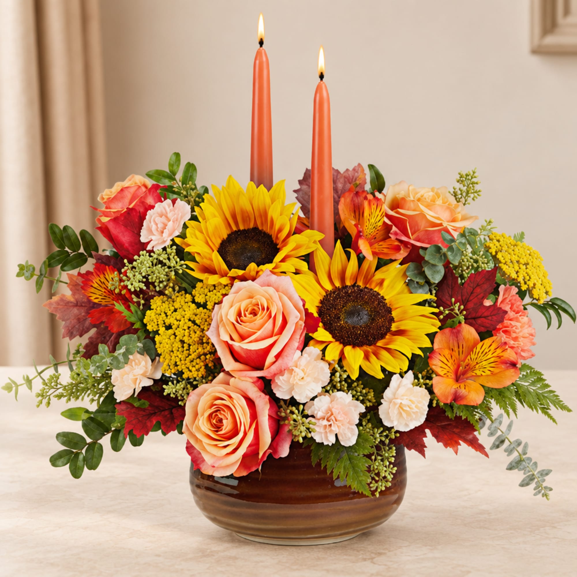 Autumn floral arrangement with sunflowers, roses, and two orange candles in a brown bowl vase