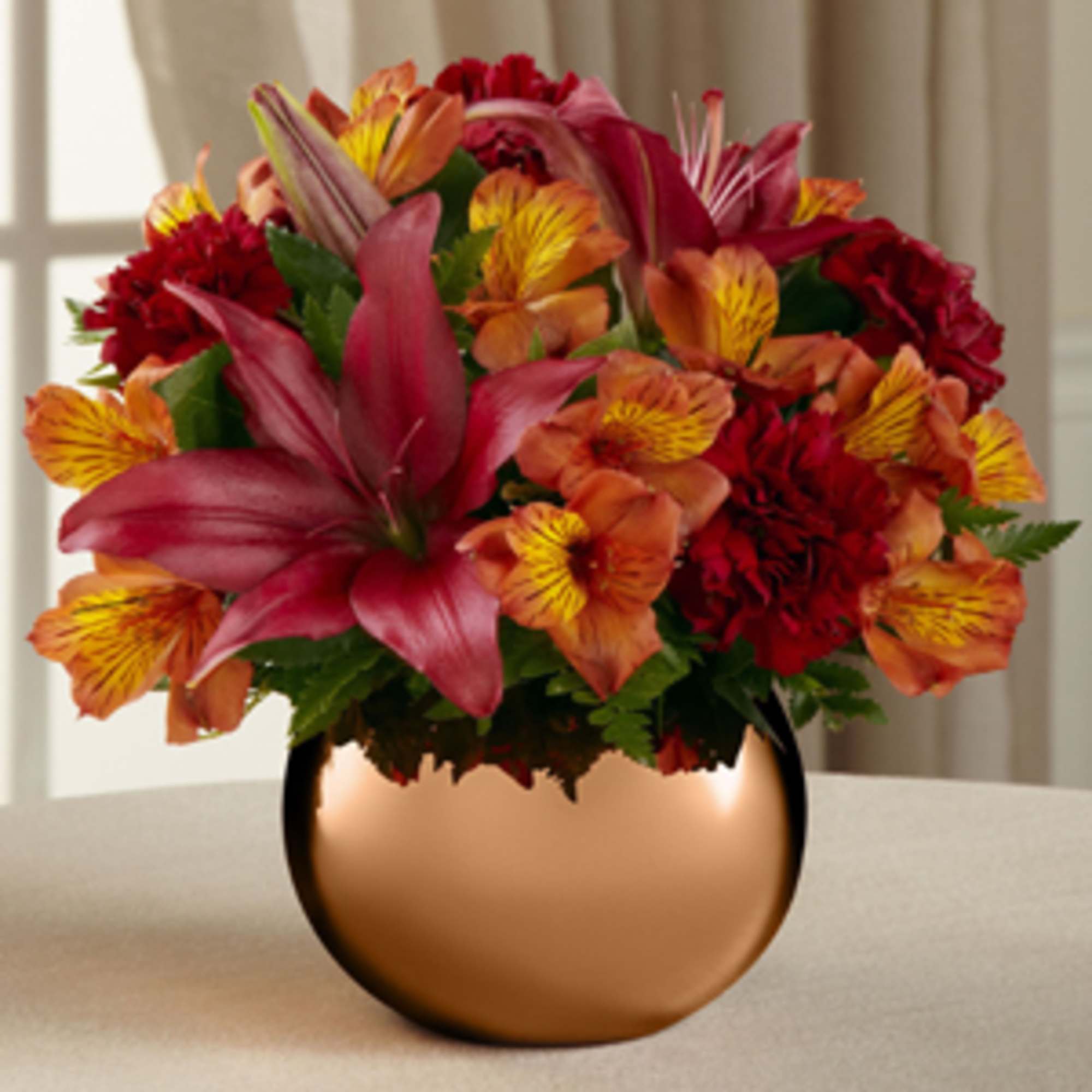 Bouquet of red, orange, and yellow flowers in a copper vase