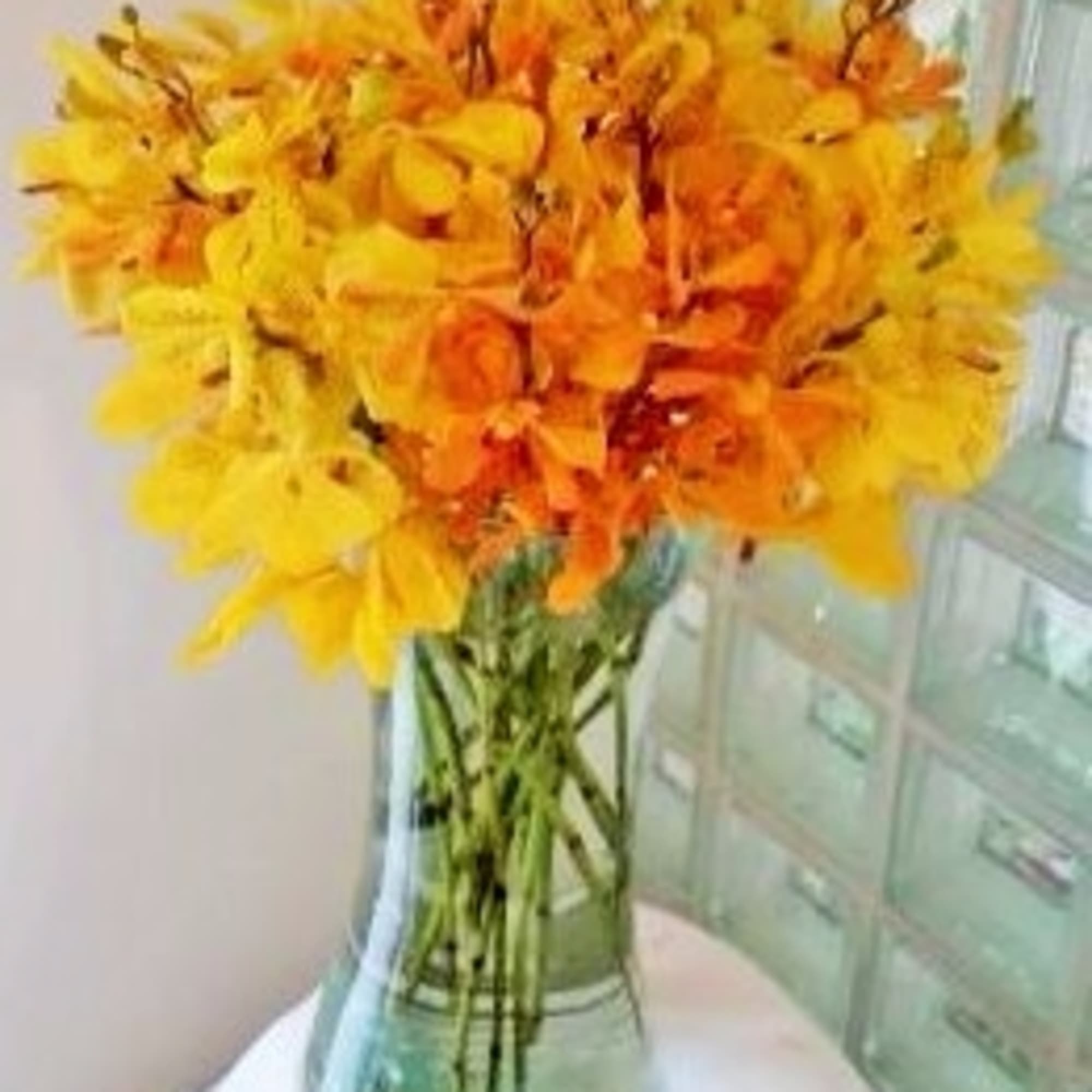 Yellow and orange flowers in a clear glass vase