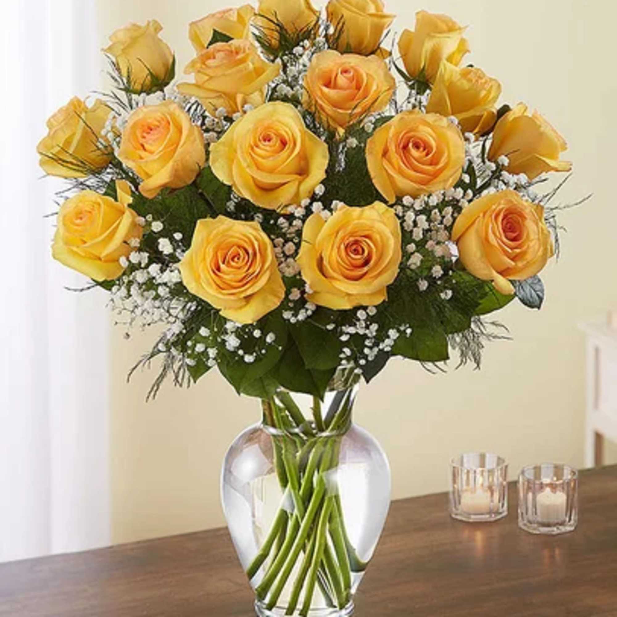Yellow roses arranged in a clear glass vase with baby's breath