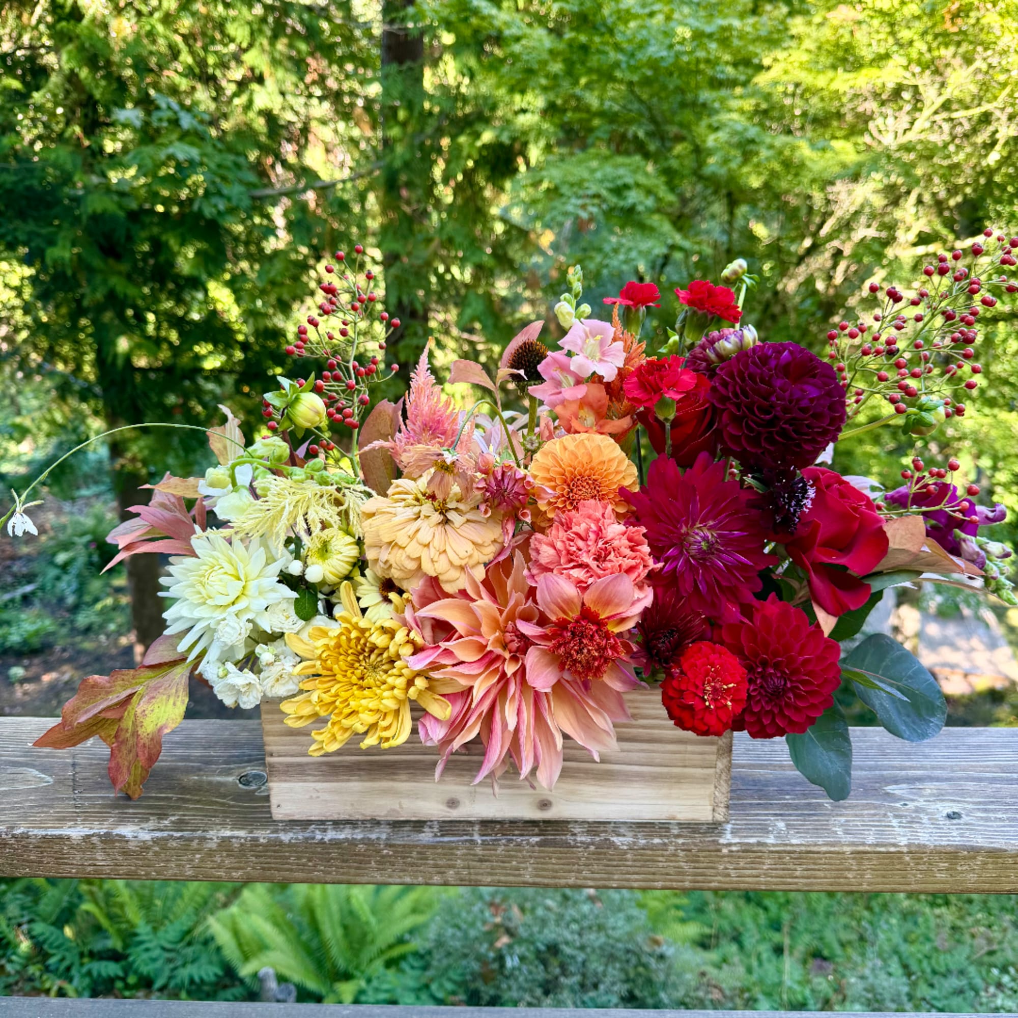 Colorful mixed flower arrangement in a wooden box on a deck