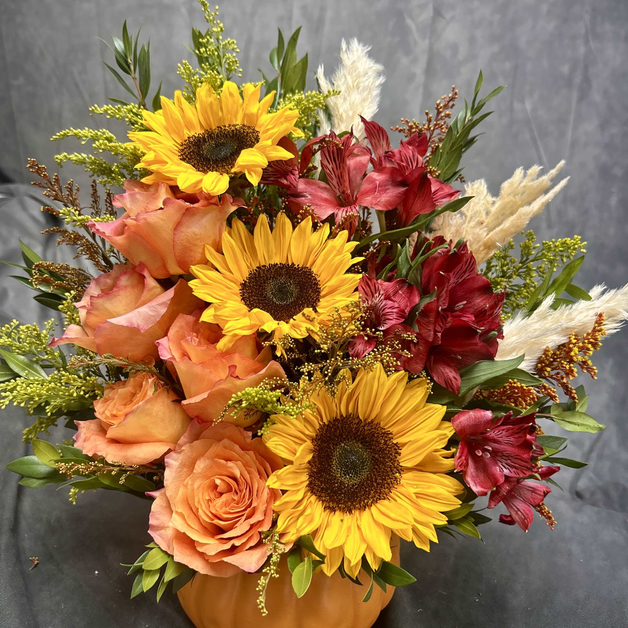 Sunflower and rose arrangement in a pumpkin-shaped container