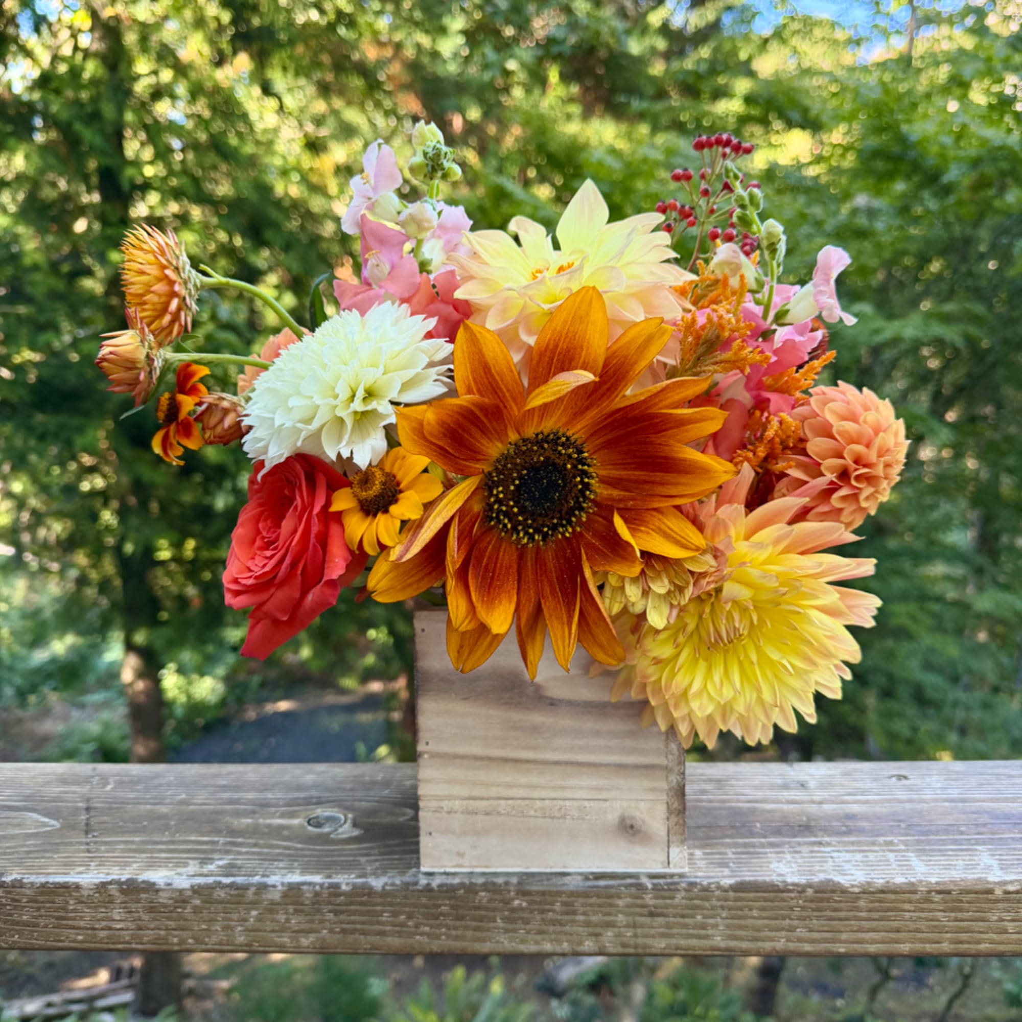 Mixed bouquet of orange, yellow, pink, and white flowers in a wooden box