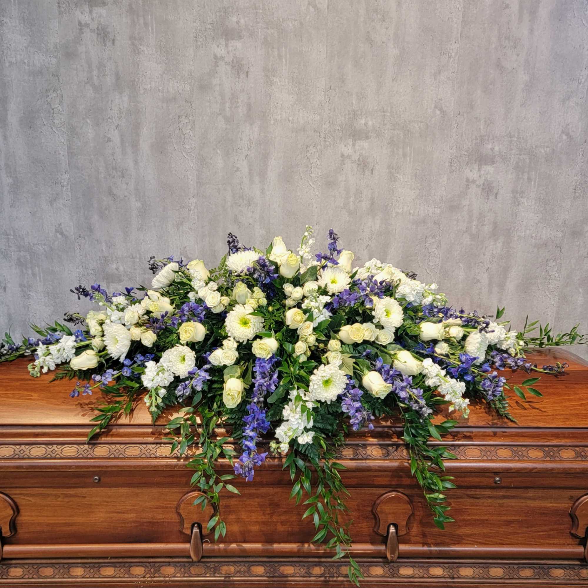 White and purple floral spray on a wooden casket