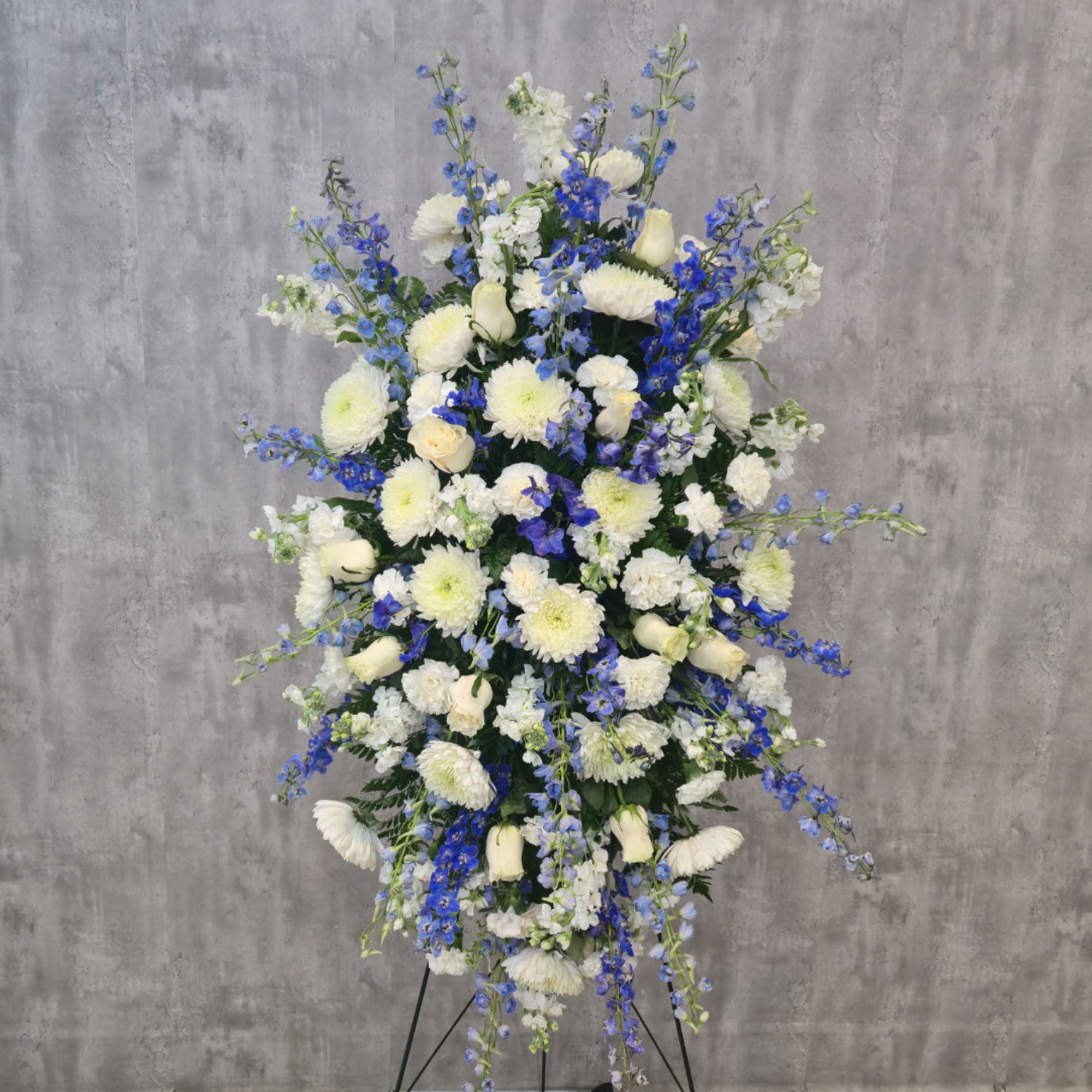 Tall white and blue floral standing arrangement on a black easel