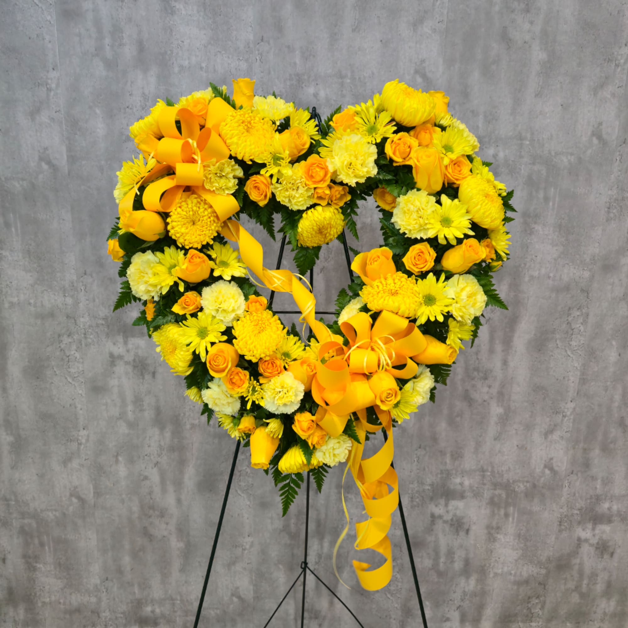 Yellow floral heart wreath on a stand with ribbon accents
