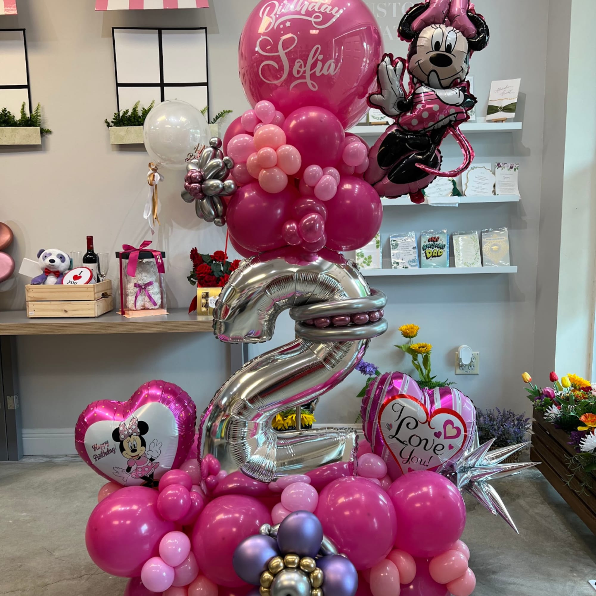 Pink birthday balloon display with Minnie Mouse balloons and a large silver number 2