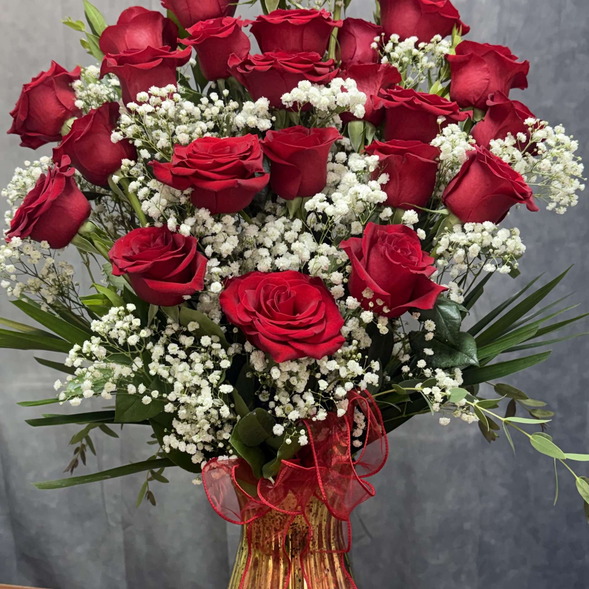 A charming mixed-rose arrangement featuring red roses accented with fresh greenery and