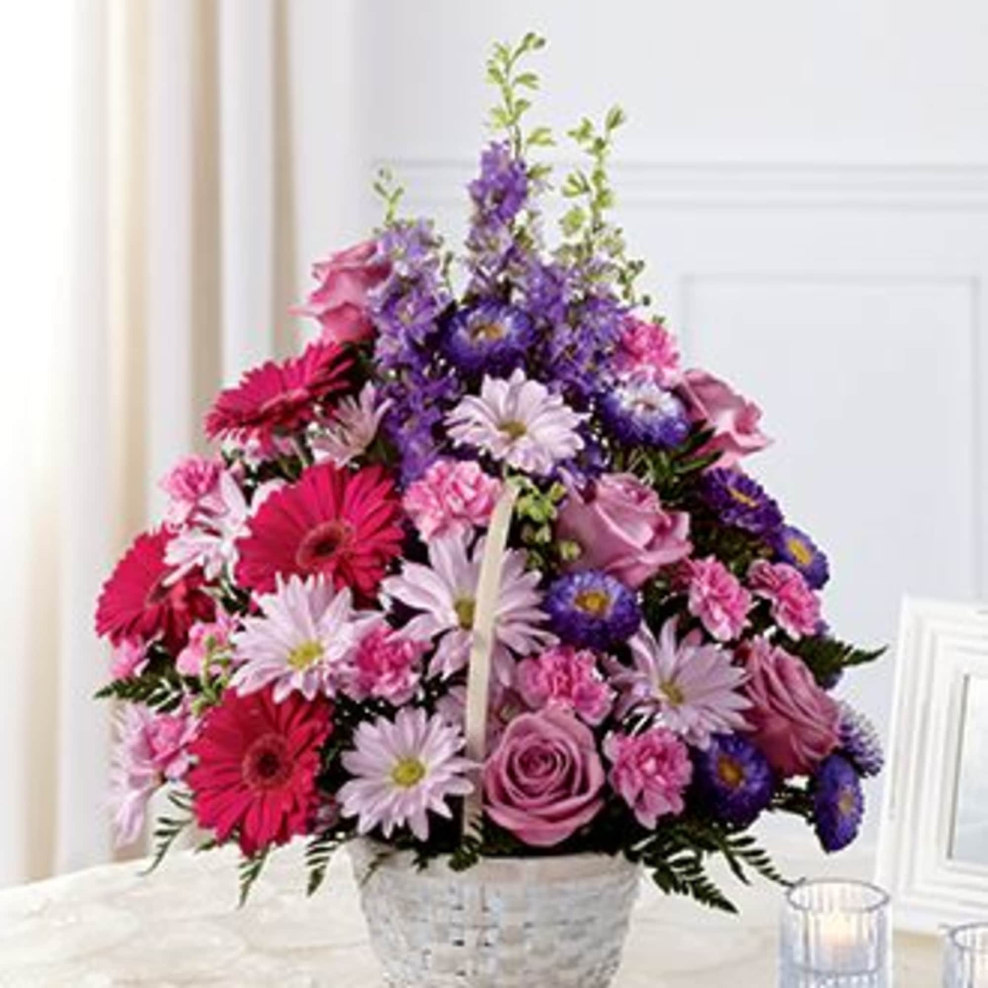 Pink and purple mixed flower basket arrangement with gerbera daisies, roses, and carnations