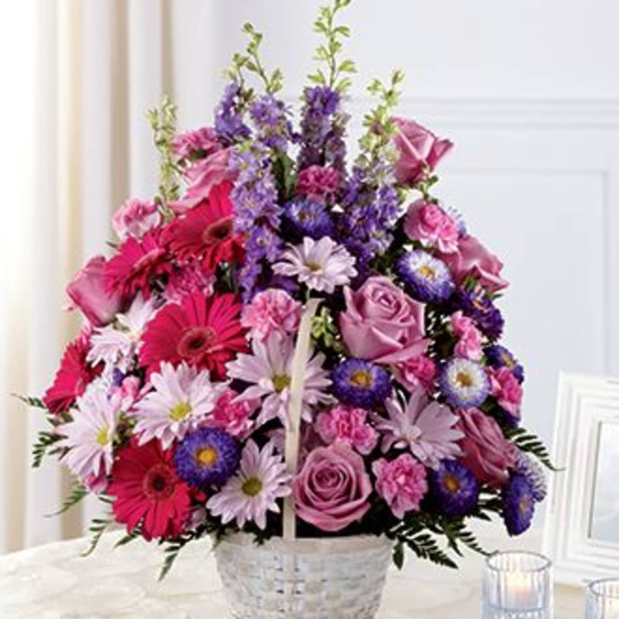 Pink and purple mixed flower basket arrangement with roses, gerberas, and daisies