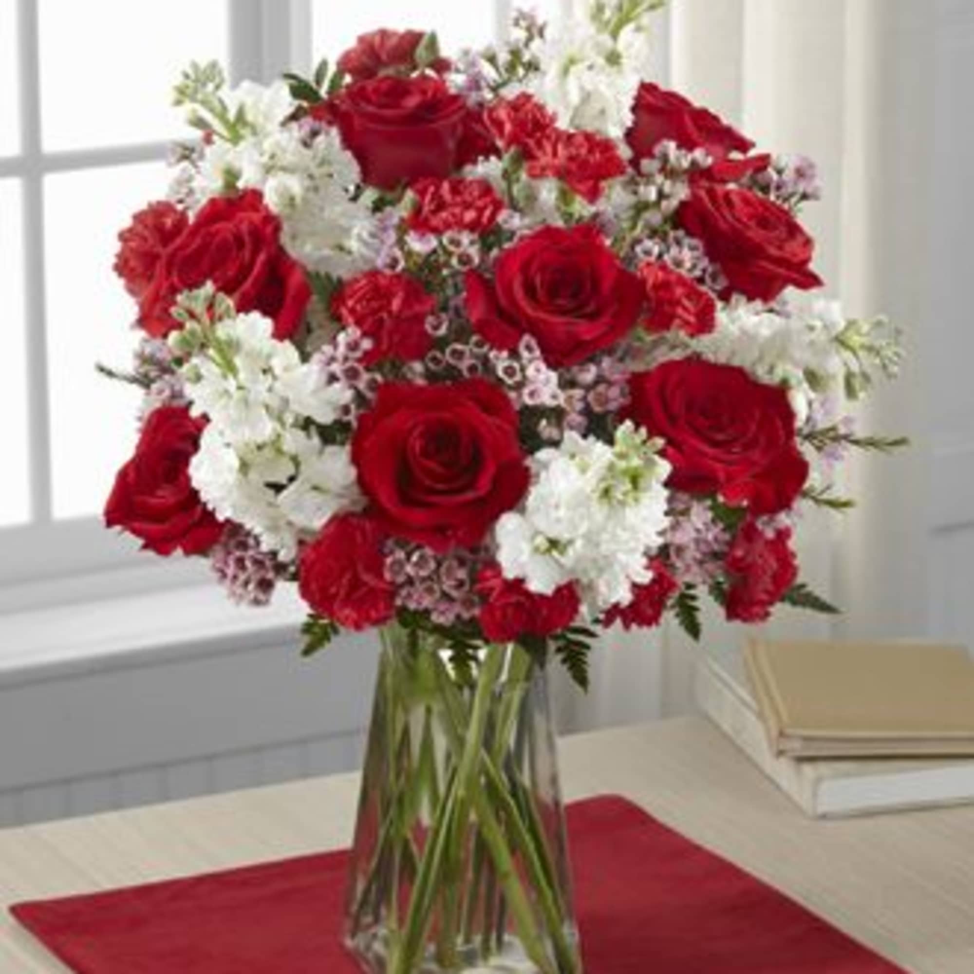 Red roses and white flowers arranged in a clear glass vase