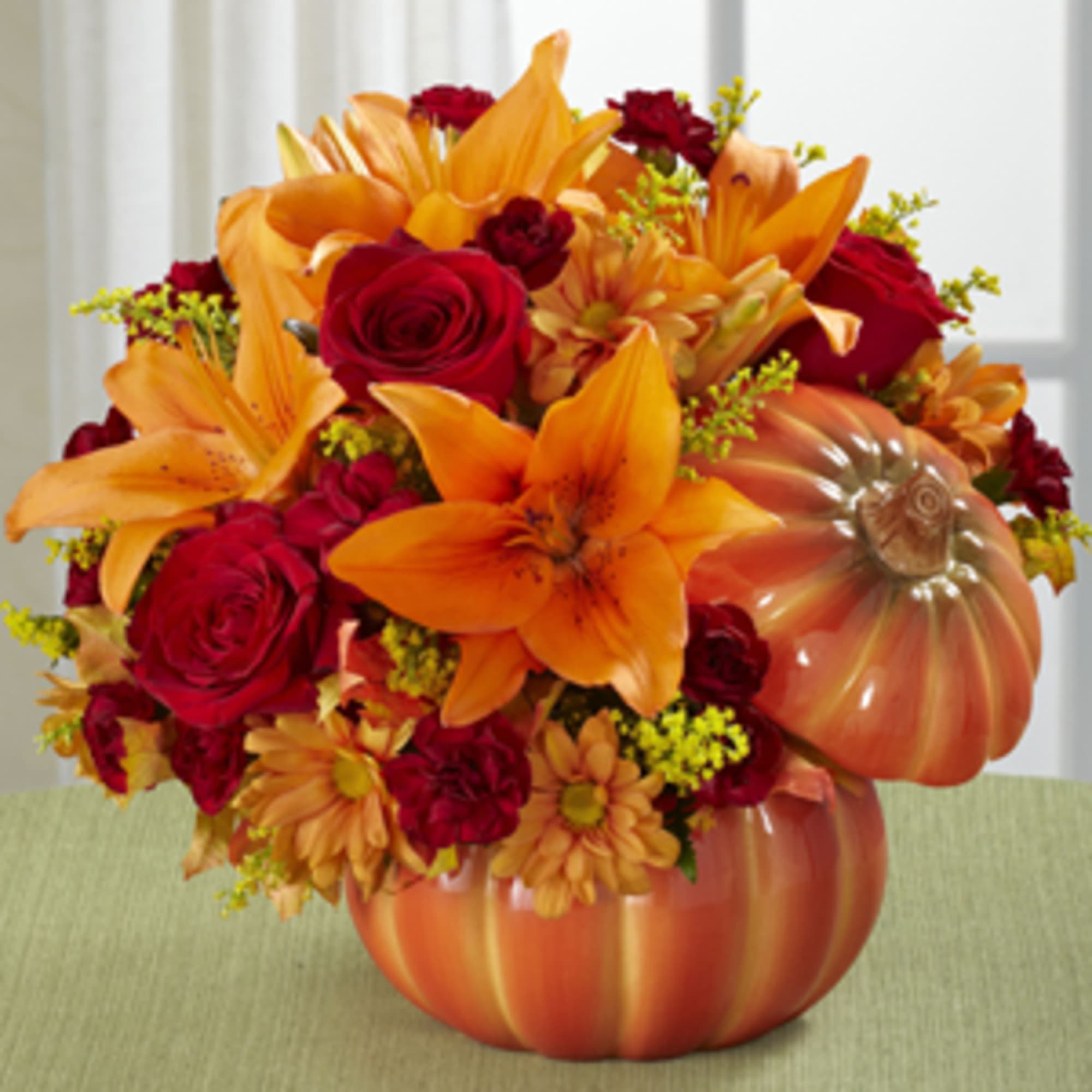 Orange and red floral arrangement in a pumpkin-shaped vase