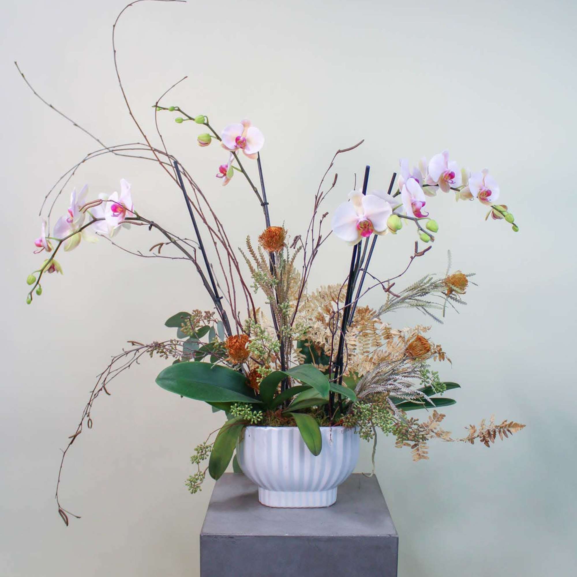Tall orchid arrangement in a white vase with arching branches