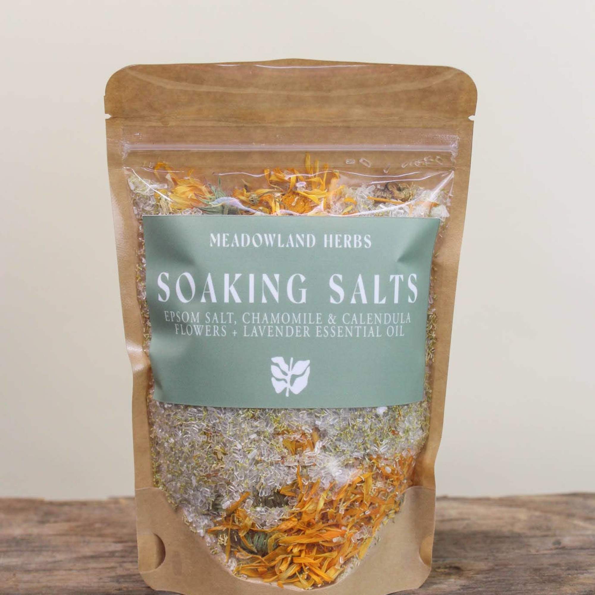 Kraft pouch of soaking salts with dried flowers visible through a clear window