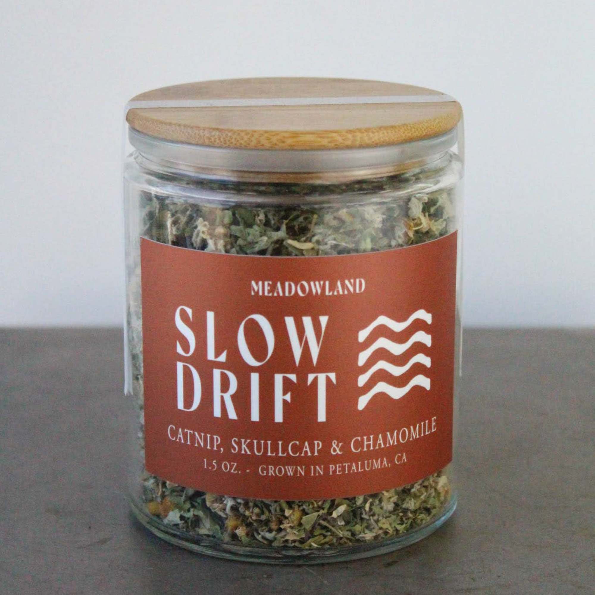 Glass jar of dried catnip and herbs with a wooden lid