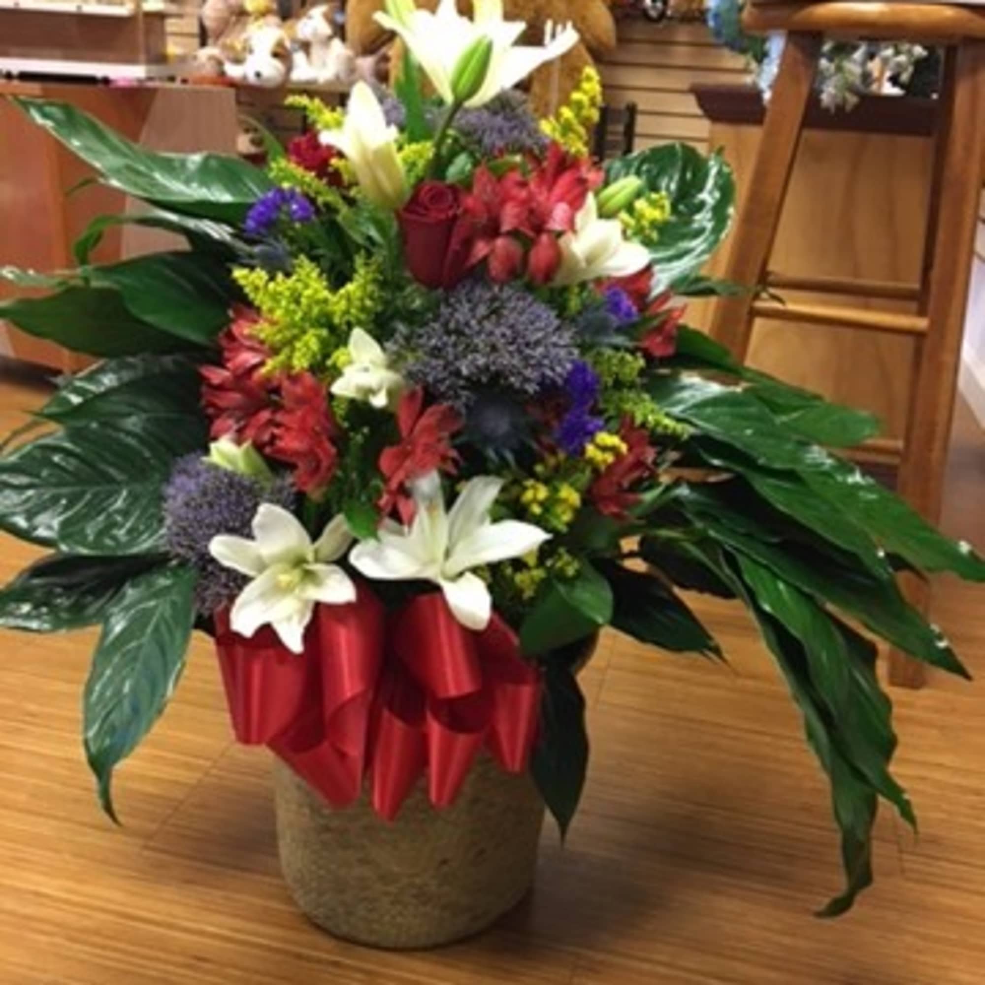 Large mixed flower arrangement with white lilies and red blooms in a vase