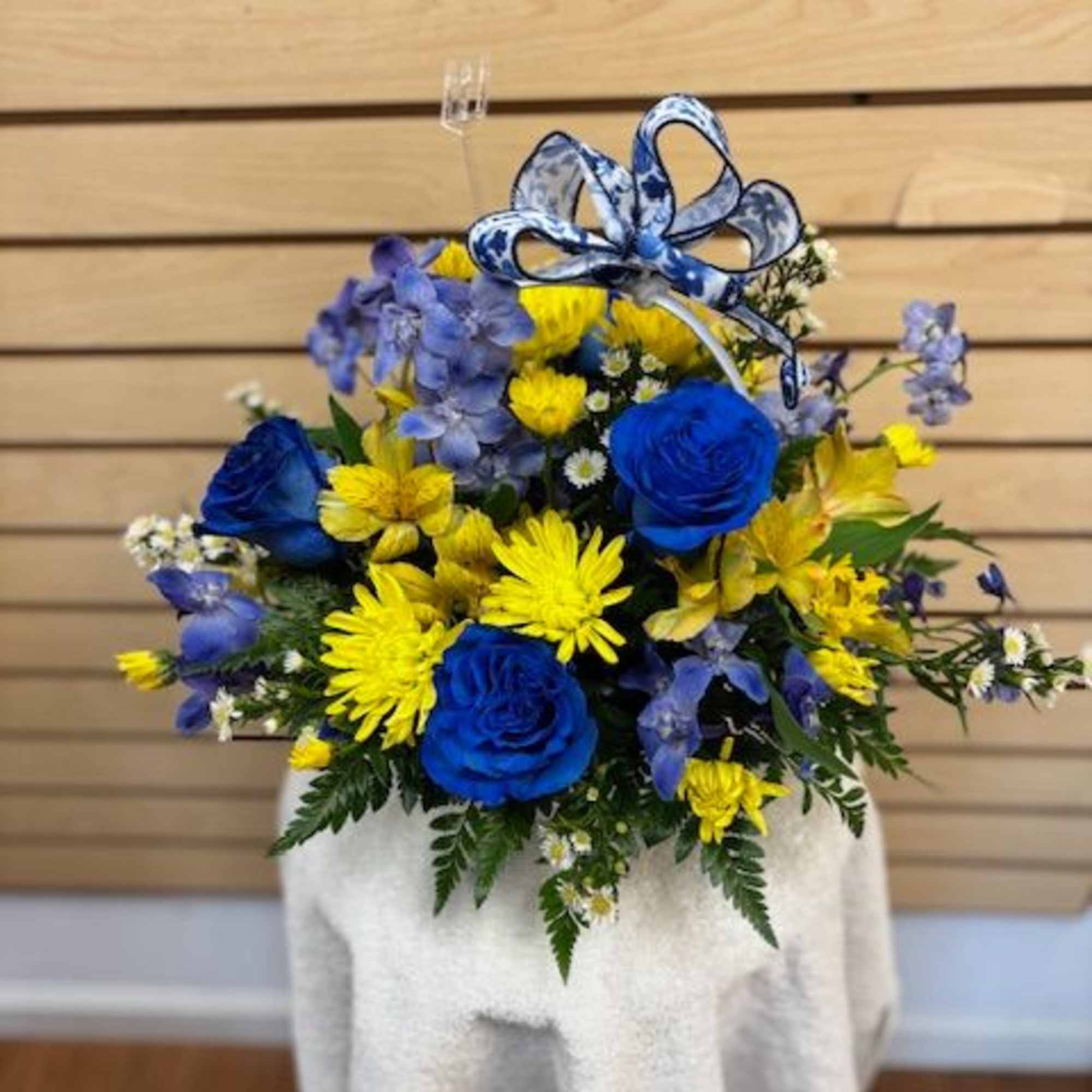Blue and yellow flower arrangement with a patterned ribbon bow